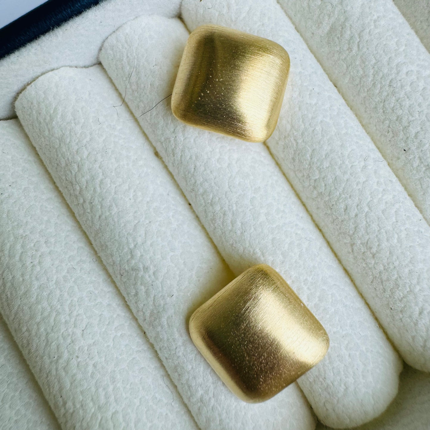 Two delicate square studs earrings displayed in a cushioned jewelry case