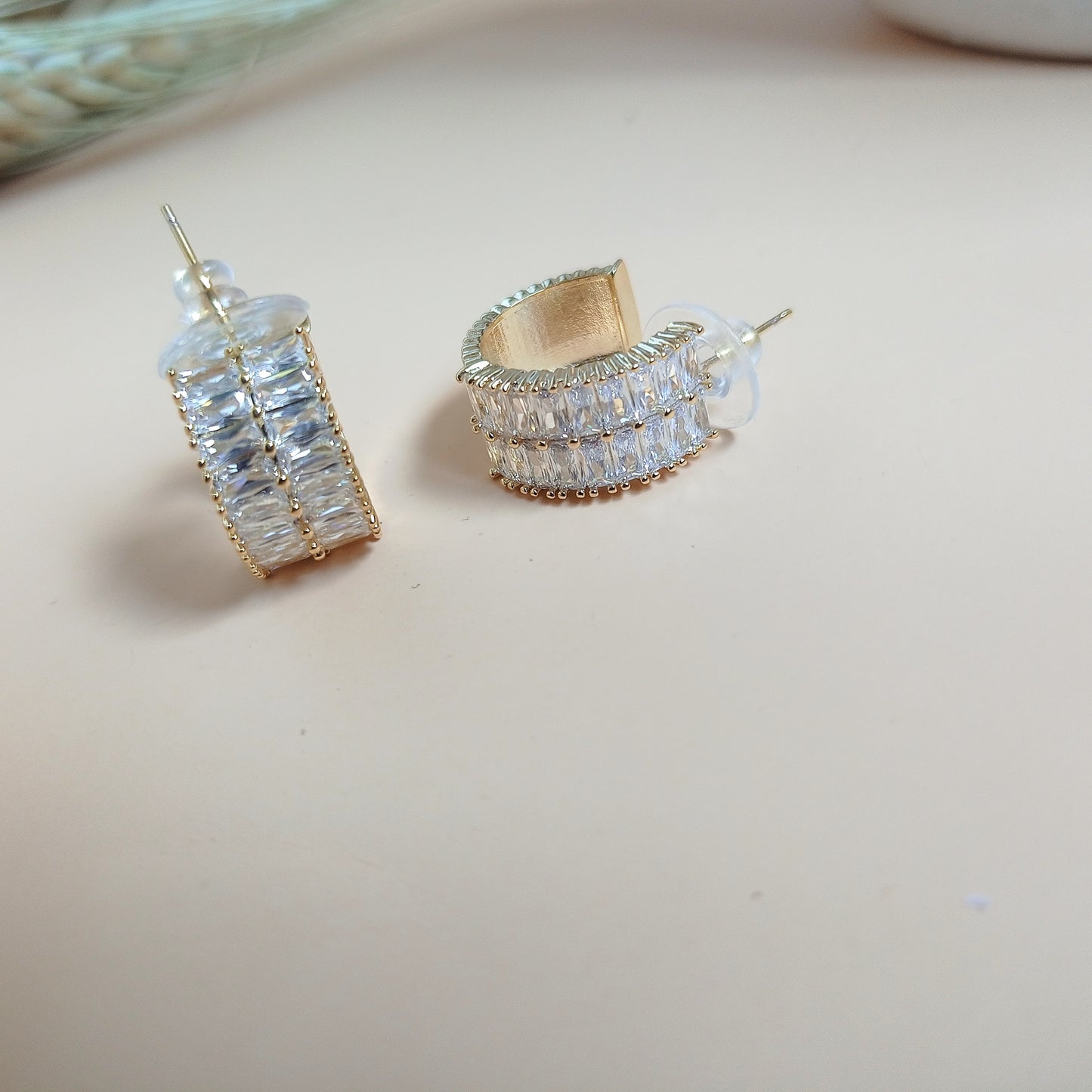 A pair of elegant gold-tone half-hoop earrings featuring baguette-cut cubic zirconia stones in a channel setting. The design combines classic sophistication with a modern touch, making them perfect for both everyday wear and special occasions.