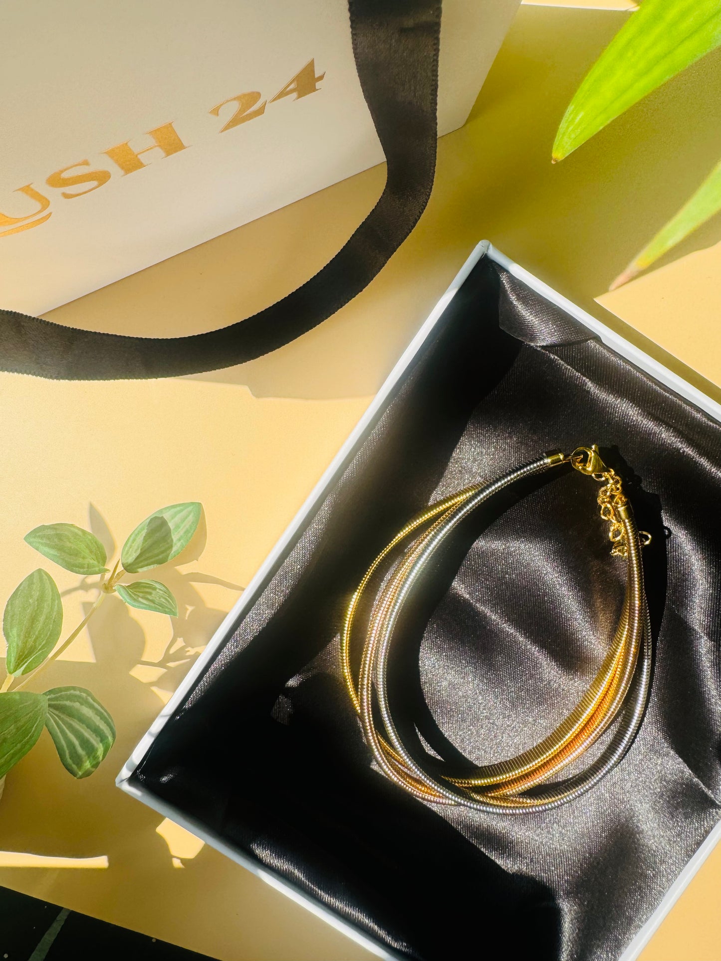 A chic triple-layer necklace from the Mumbai-based brand Lush 24, featuring delicate chains in bronze, silver, and gold. This versatile necklace is presented in a luxurious gift box with a black satin lining.