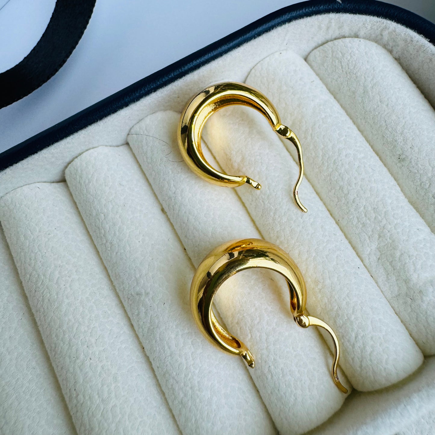 Classic gold stud earrings with a sleek, minimalist design, displayed in an elegant jewelry case for a timeless and sophisticated look