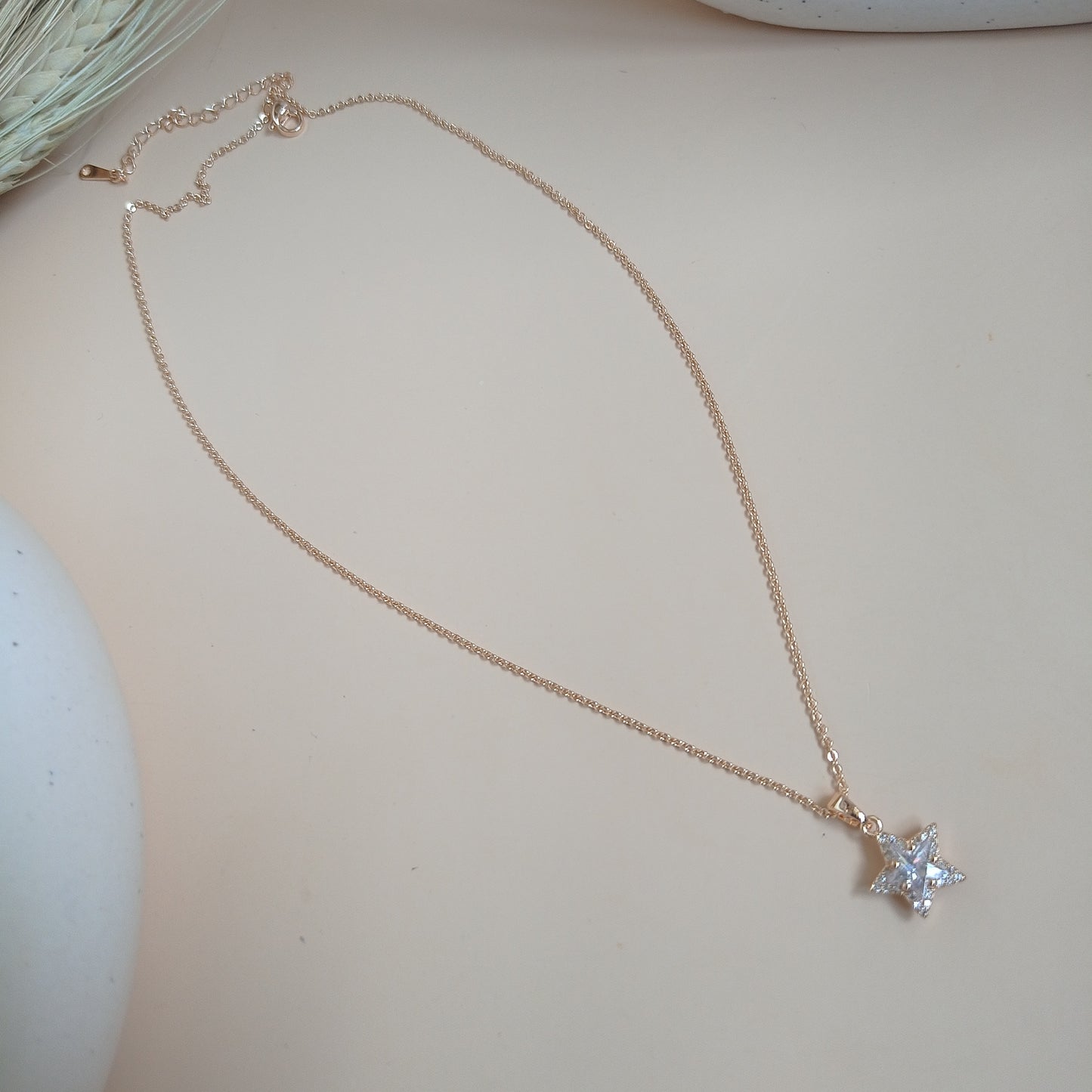 Rose gold necklace featuring a dazzling star-shaped pendant adorned with sparkling white stones, set against a soft neutral background