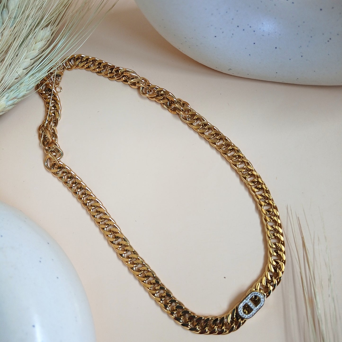 Gold-tone Cuban link chain necklace with a central embellished clasp detail, displayed on a neutral background