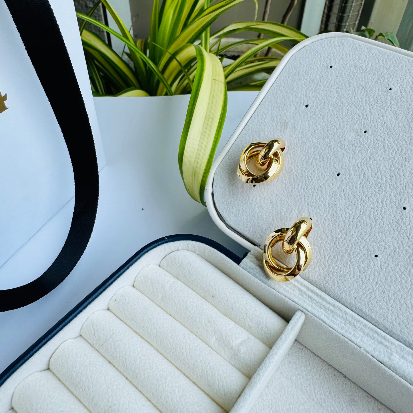 Two polished gold hoop earrings displayed in a cushioned jewelry case