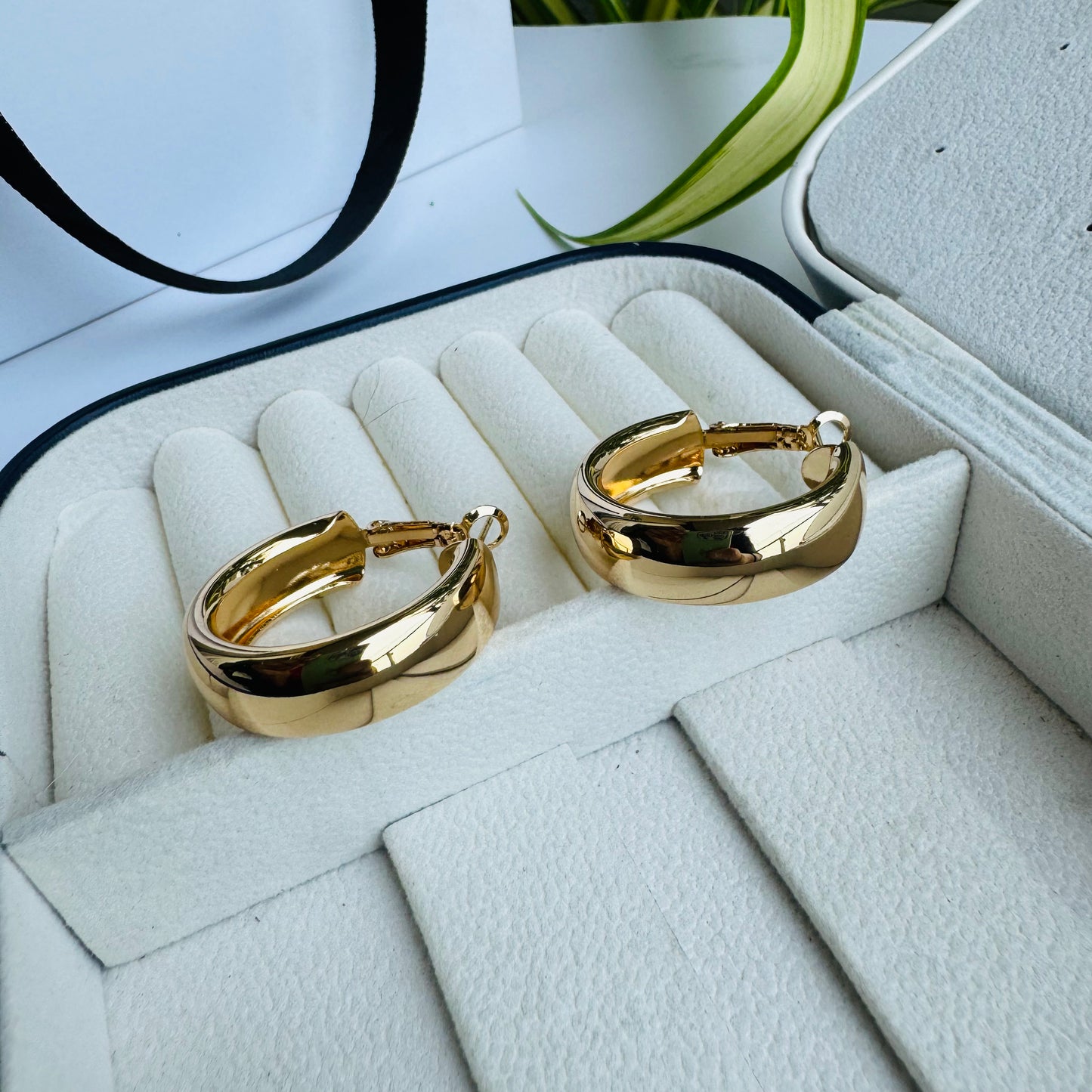 Pair of shiny gold hoop earrings in a white and black jewelry case