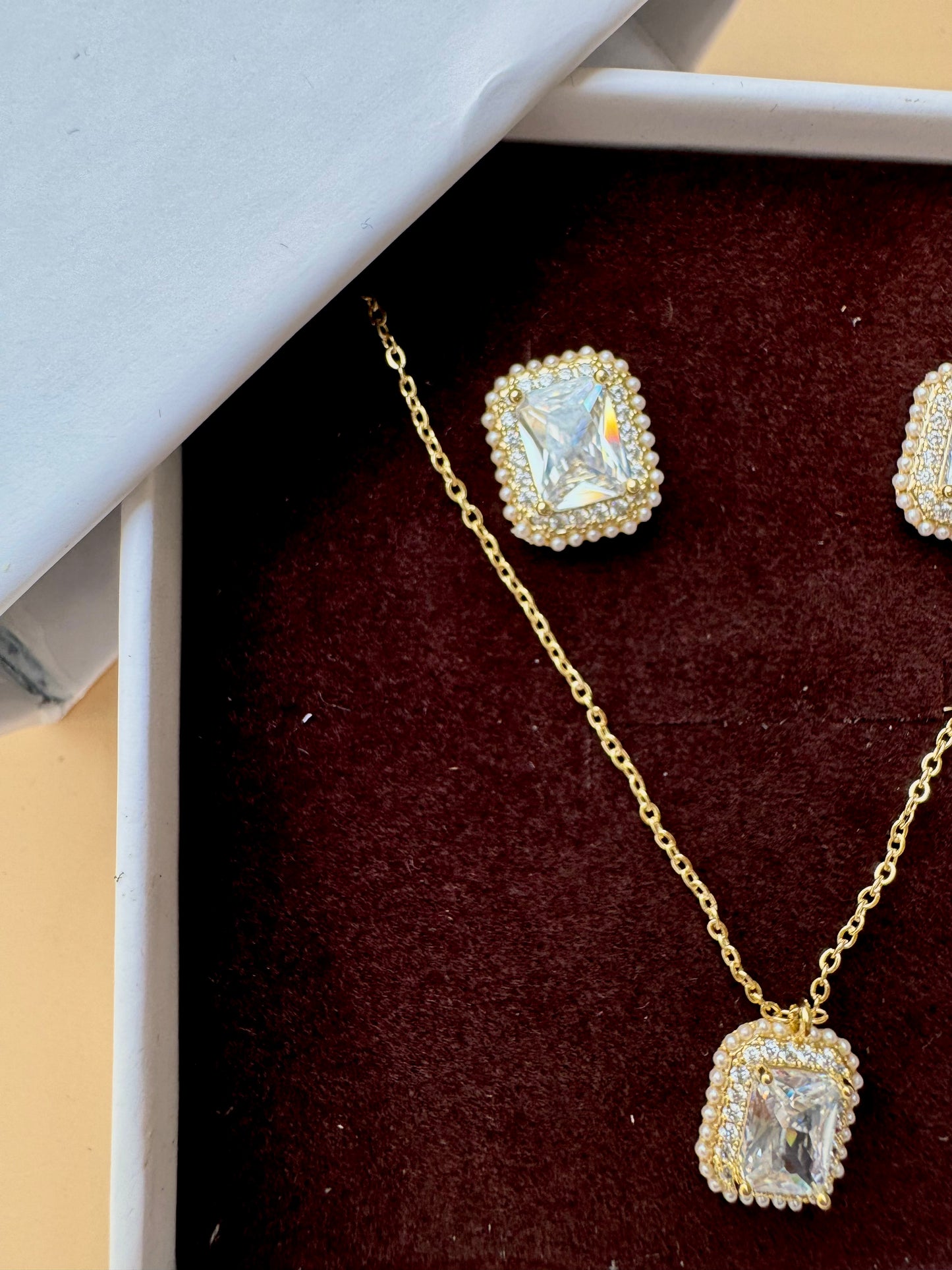Elegant flower-shaped crystal pendant necklace and earring set displayed in a light blue and white LUSH 24 gift box.