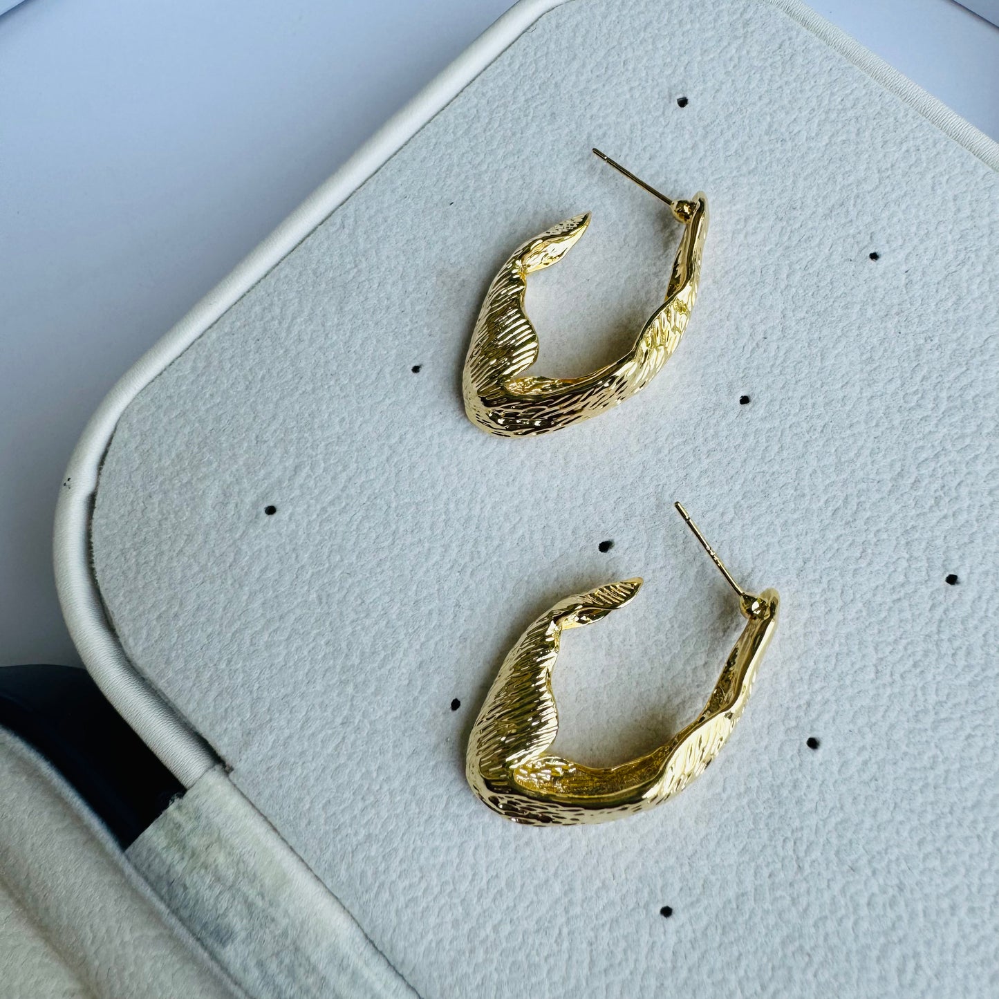 Abstractly shaped gold earrings displayed on a jewelry stand