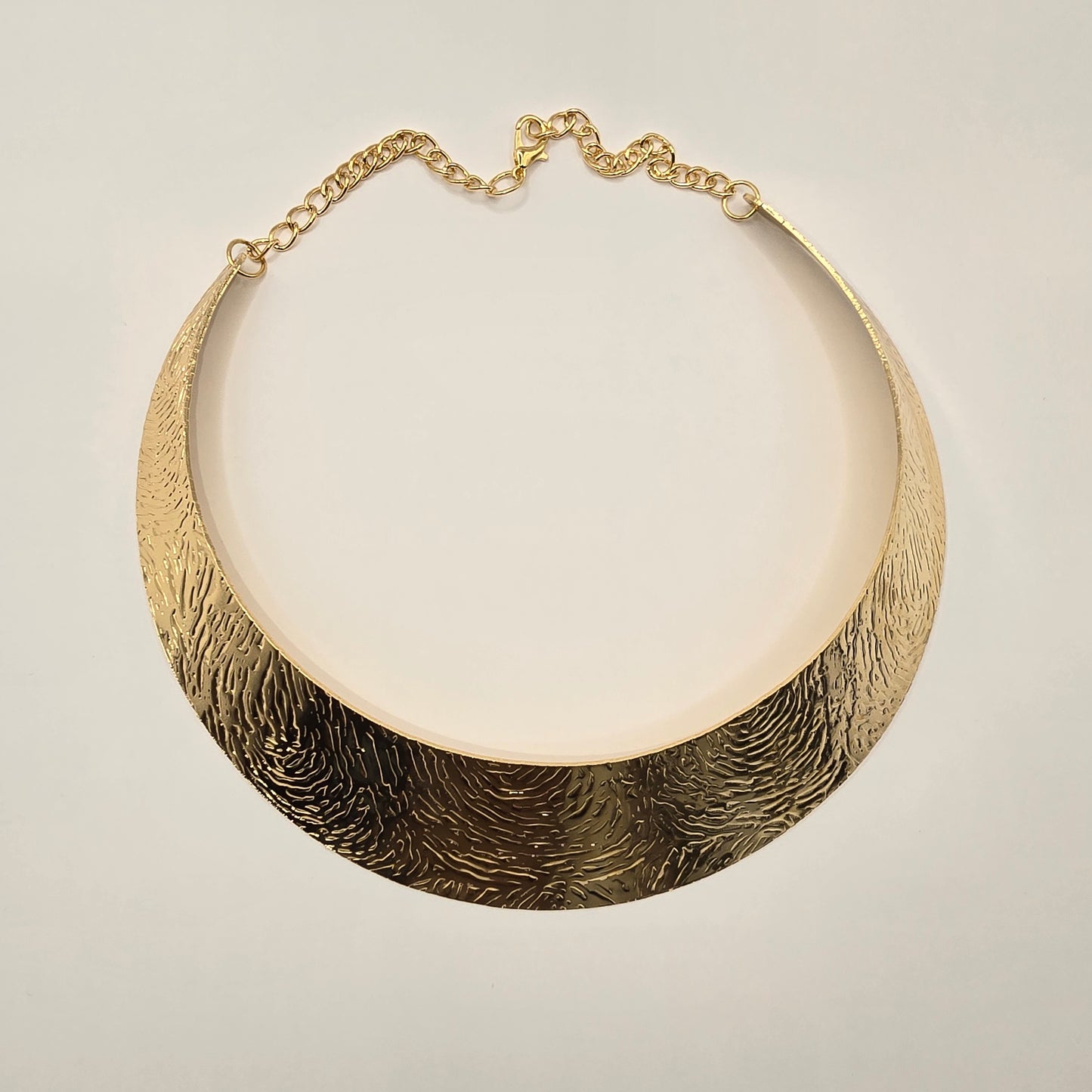 A dramatic gold metallic collar necklace with radiating spikes is displayed on a white mannequin bust. Lush 24 branded shopping bags and a jewelry box are visible in the background.