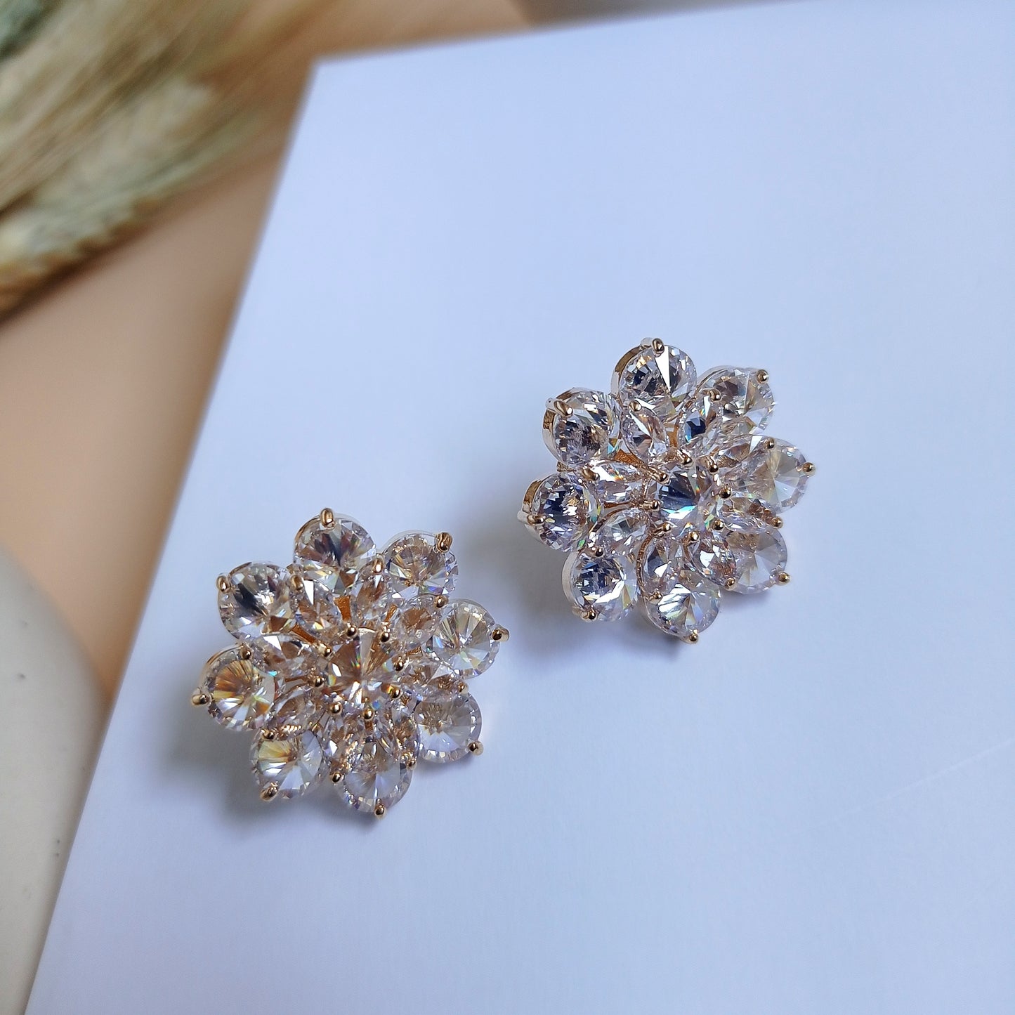 Pair of gold-tone floral stud earrings adorned with sparkling marquise-cut and round-cut cubic zirconia stones, creating a luxurious and elegant look. Perfect for special occasions or adding a touch of glamour to any outfit.