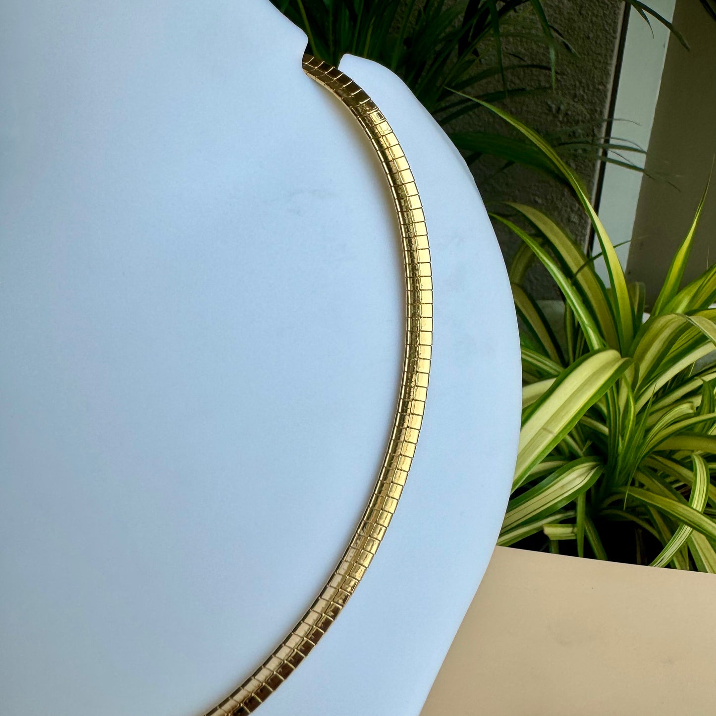 Elegant gold chain necklace displayed on a white bust.