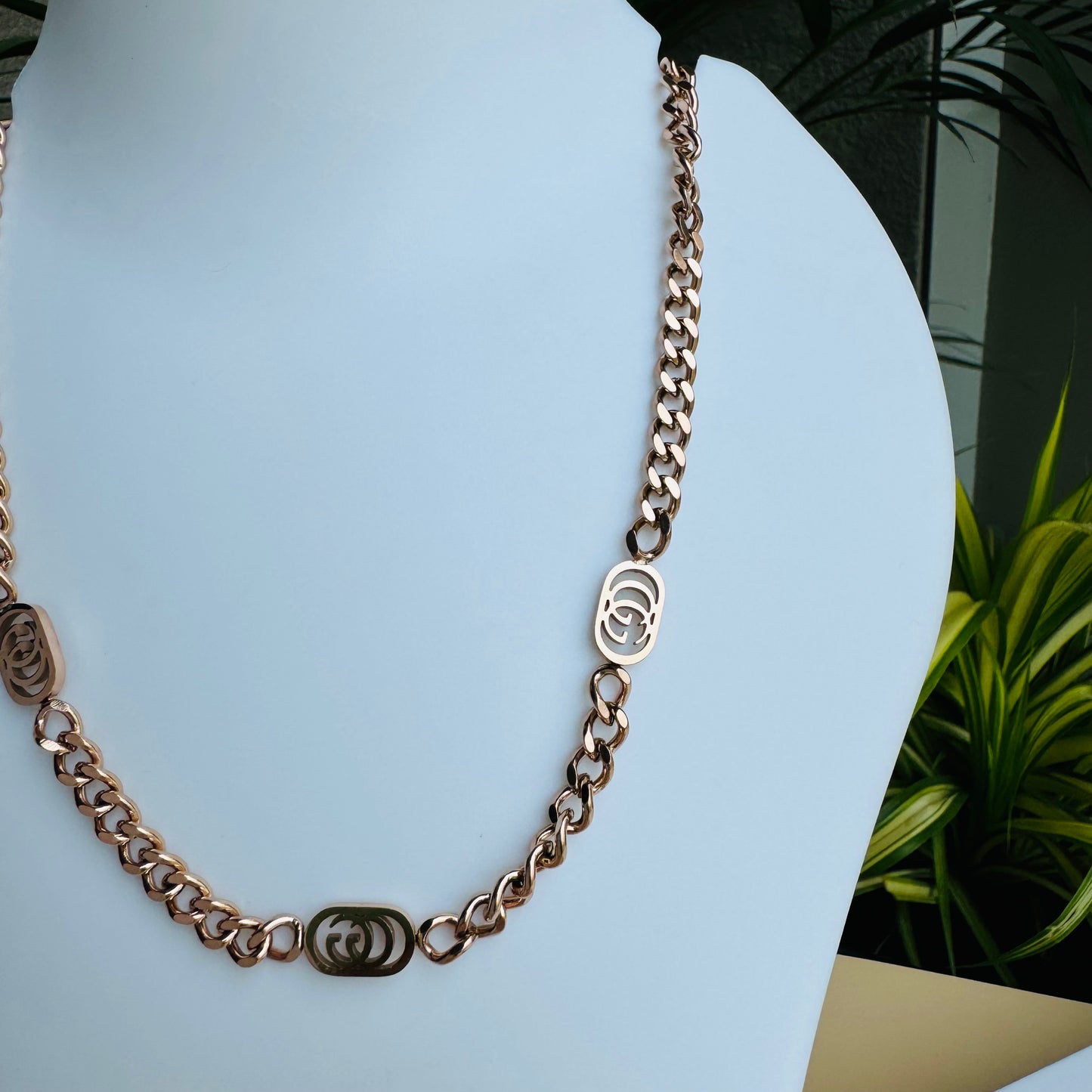 A stylish rose gold chain necklace with delicate interlocking circular accents, displayed on a white jewelry bust with elegant Lush 24 packaging in the background