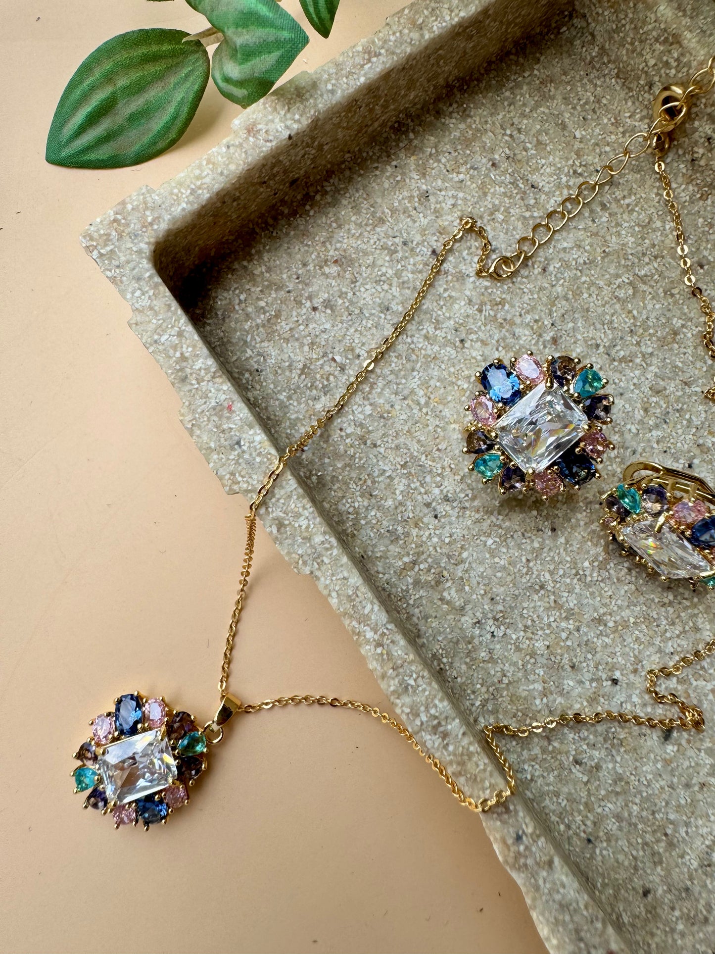 Close-up of a LUSH 24 jewelry set containing a delicate multi-toned necklace with a crystal-encrusted flower pendant and matching crystal flower stud earrings, neatly arranged in a branded box.
