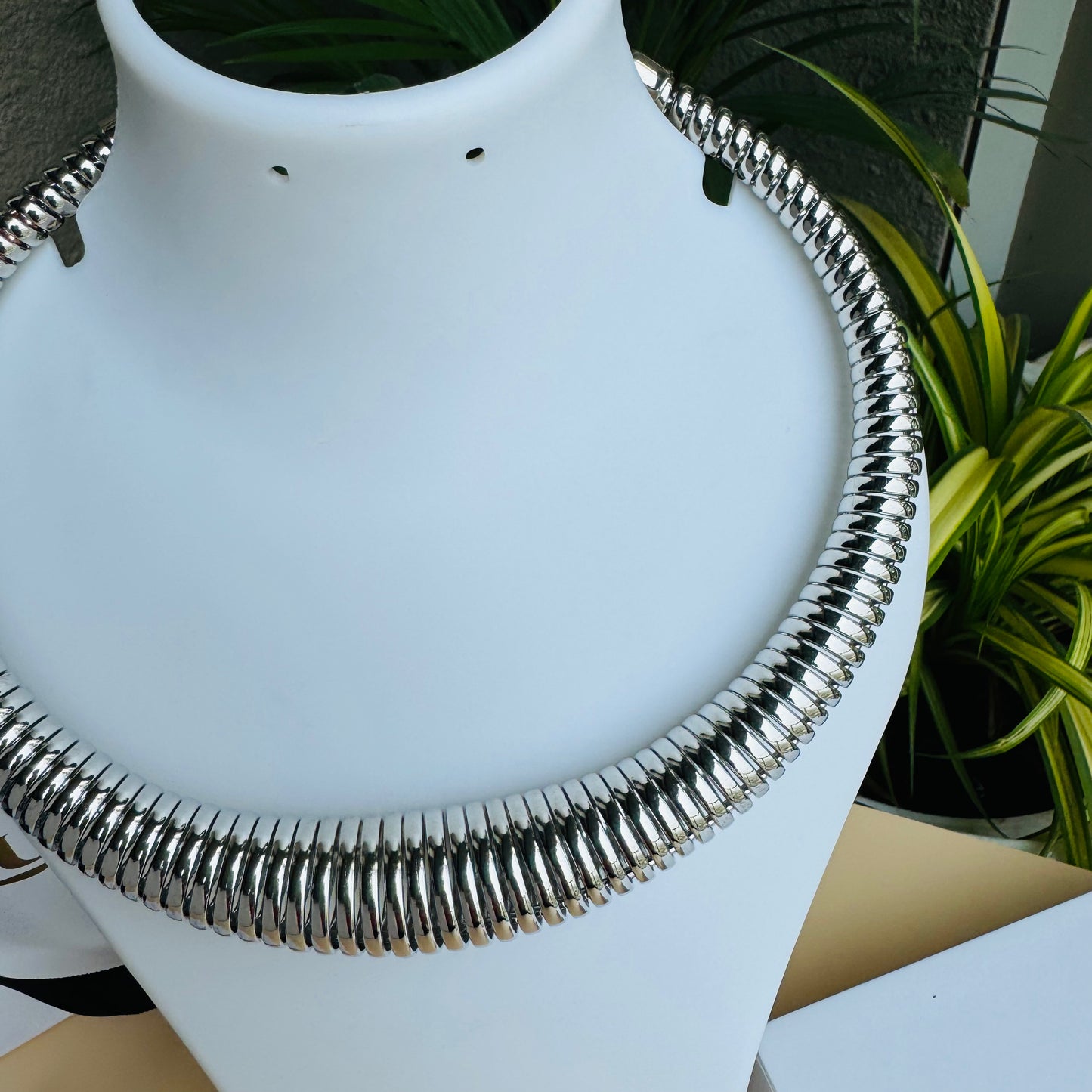 Silver-tone tubular choker necklace on a white display bust