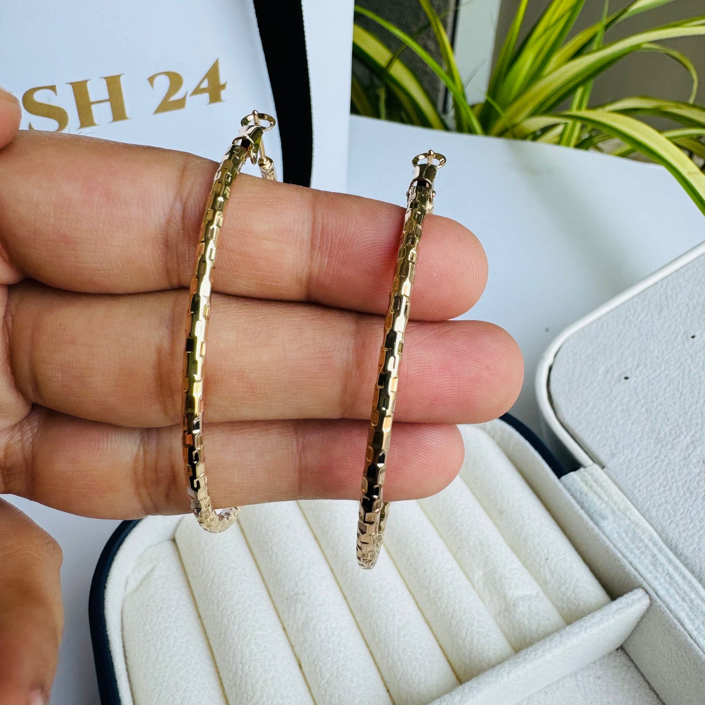 Elegant textured gold hoop earrings displayed in a luxurious jewelry case, showcasing their classic yet modern appea
