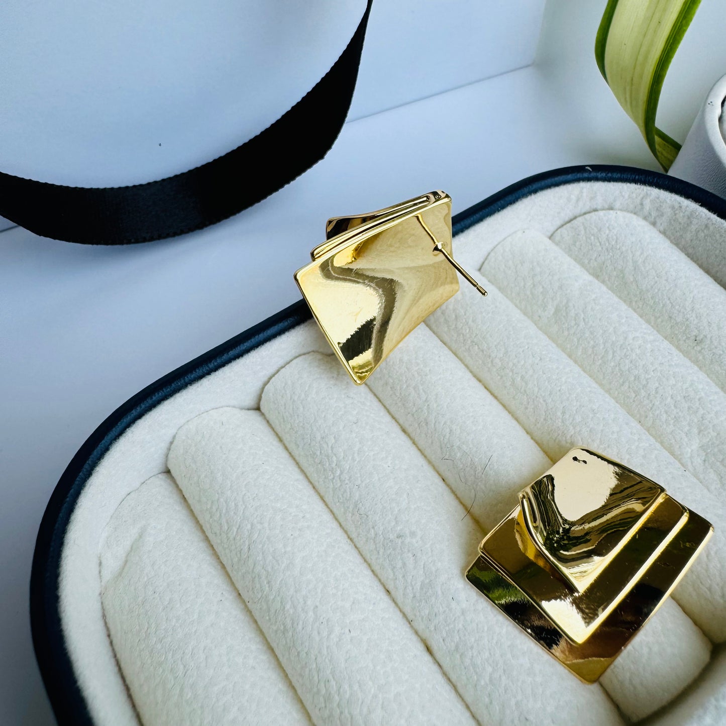 Bold geometric gold earrings with a layered square design, exuding modern elegance, displayed in a plush jewelry box