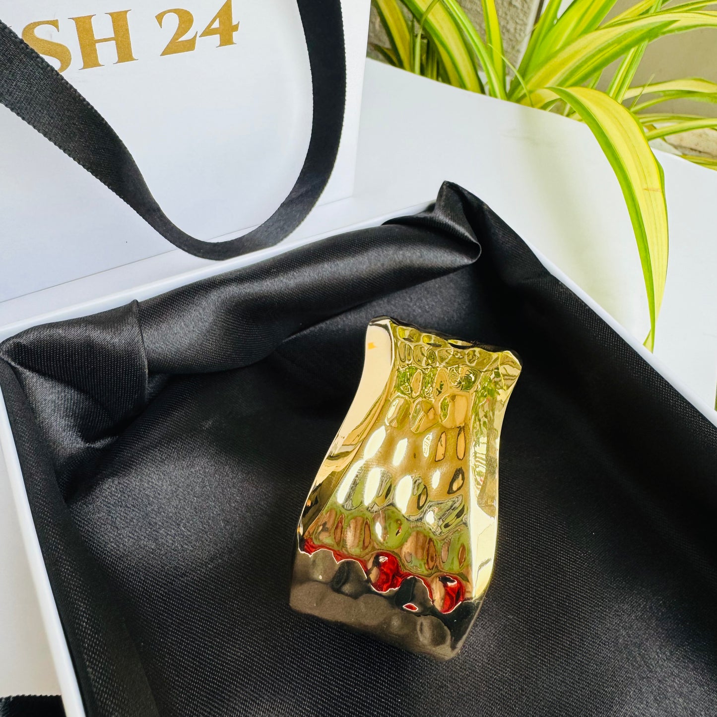 gold-toned, flexible tubular bracelet on a white display.