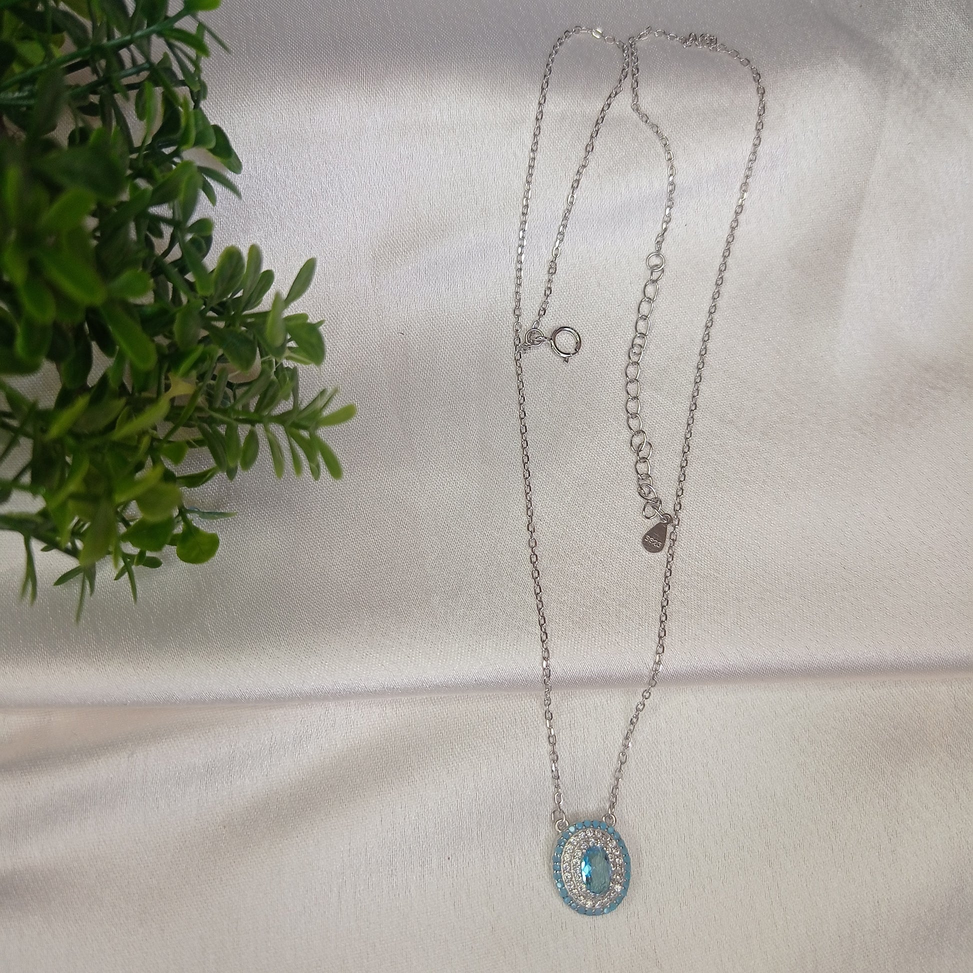 Stylish silver necklace featuring an evil eye pendant encrusted with blue and white crystals, elegantly worn for a protective and fashionable look