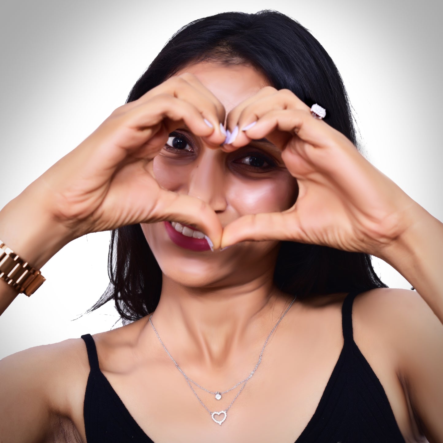 Elegant layered silver necklace featuring a delicate solitaire pendant on the upper chain and a sparkling crystal-studded heart pendant on the lower chain, adding a touch of sophistication and charm