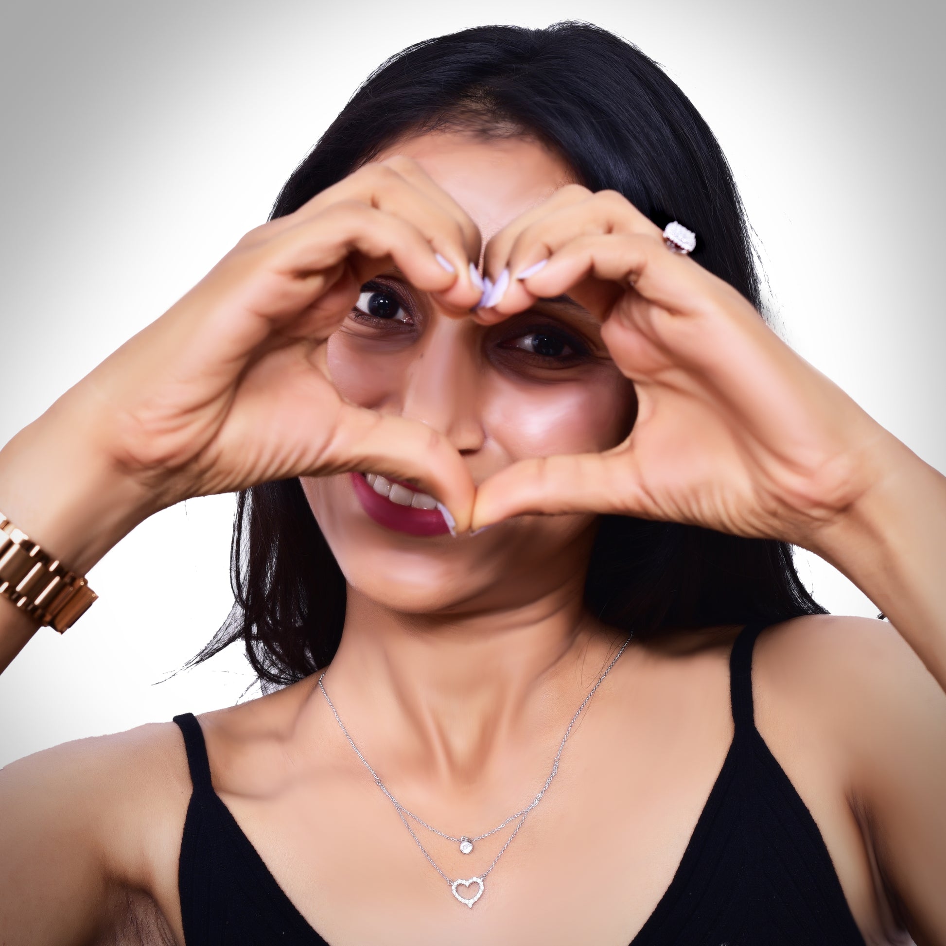 Elegant layered silver necklace featuring a delicate solitaire pendant on the upper chain and a sparkling crystal-studded heart pendant on the lower chain, adding a touch of sophistication and charm