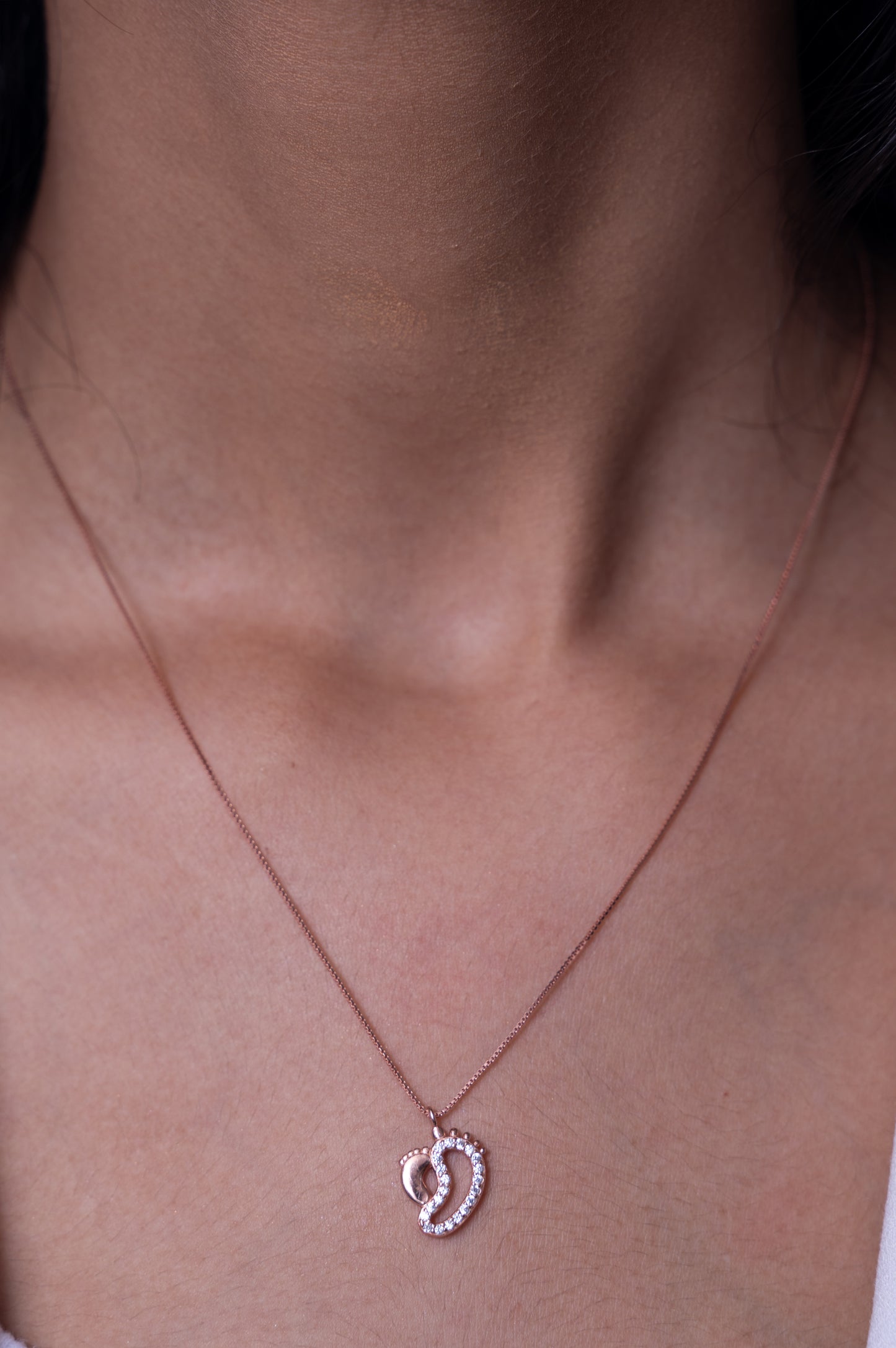 Delicate rose gold necklace with an intertwined heart pendant encrusted with shimmering crystals, symbolizing love and elegance