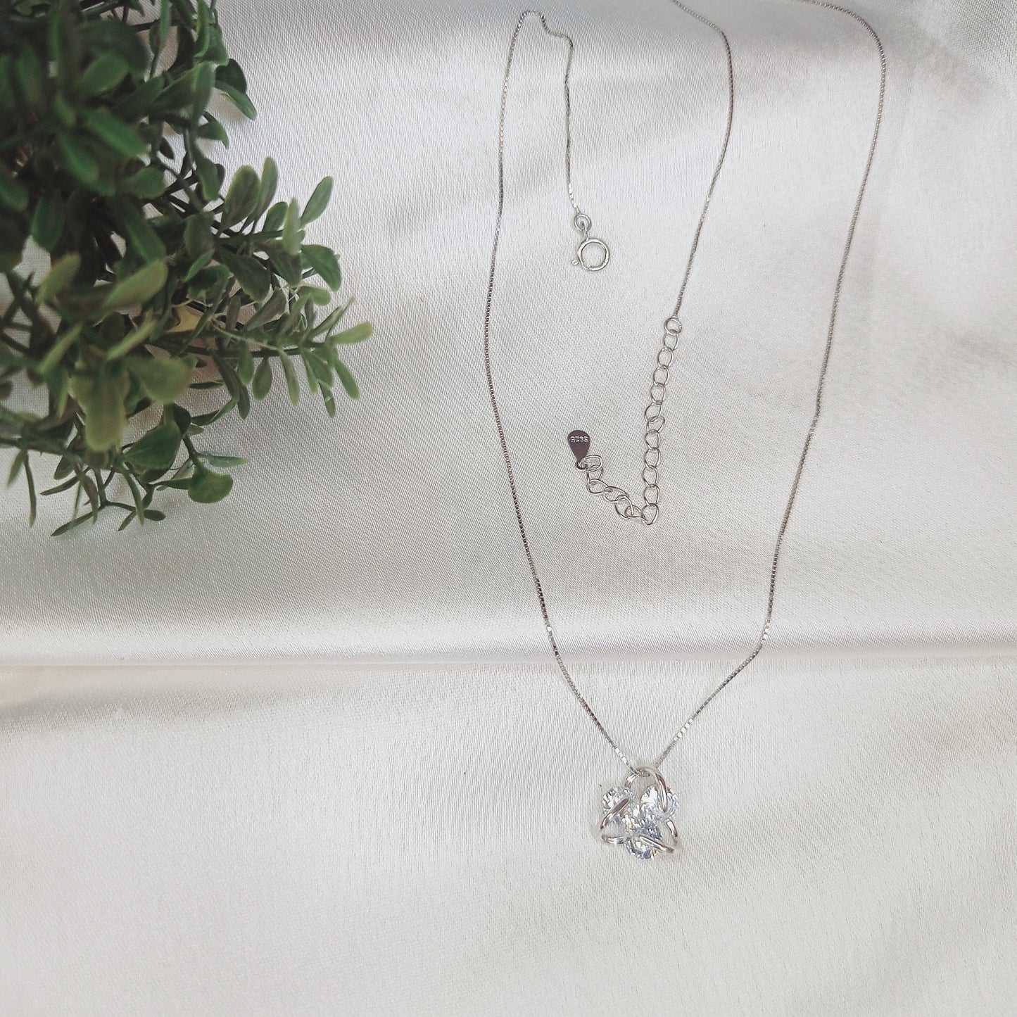 Delicate silver necklace featuring a sparkling floral pendant, elegantly worn with a black outfit. A timeless jewelry piece perfect for everyday wear or special occasions