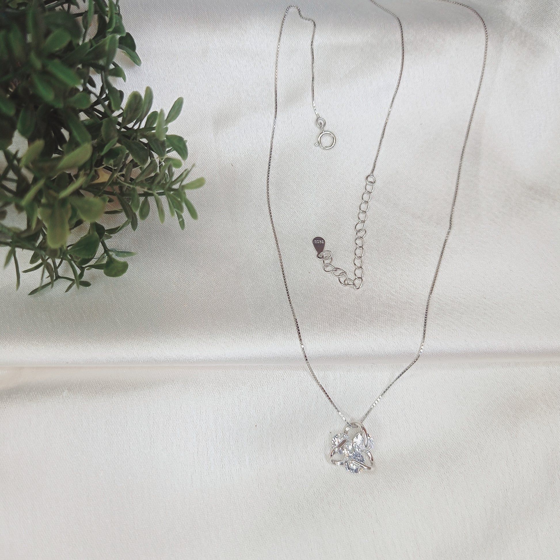Delicate silver necklace featuring a sparkling floral pendant, elegantly worn with a black outfit. A timeless jewelry piece perfect for everyday wear or special occasions