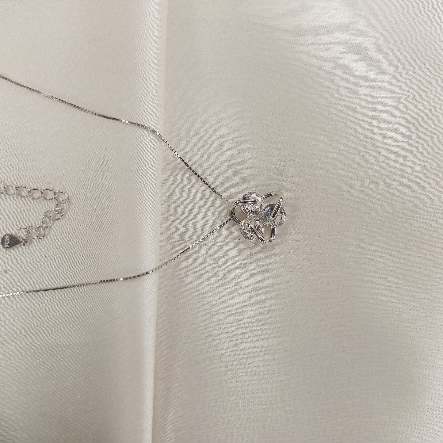 Delicate silver necklace featuring a sparkling floral pendant, elegantly worn with a black outfit. A timeless jewelry piece perfect for everyday wear or special occasions
