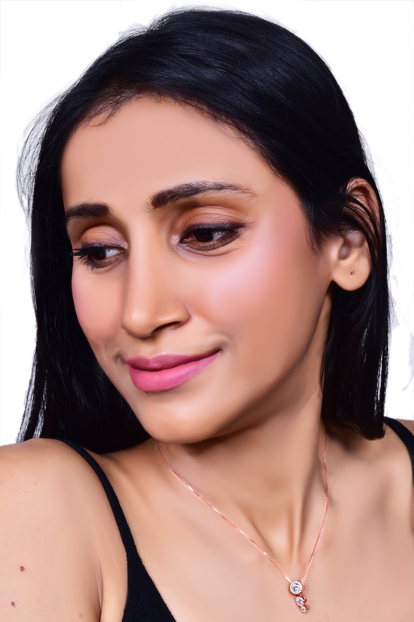 Elegant rose gold necklace featuring a three-stone drop pendant adorned with sparkling crystals, gracefully worn with a black outfit for a sophisticated look