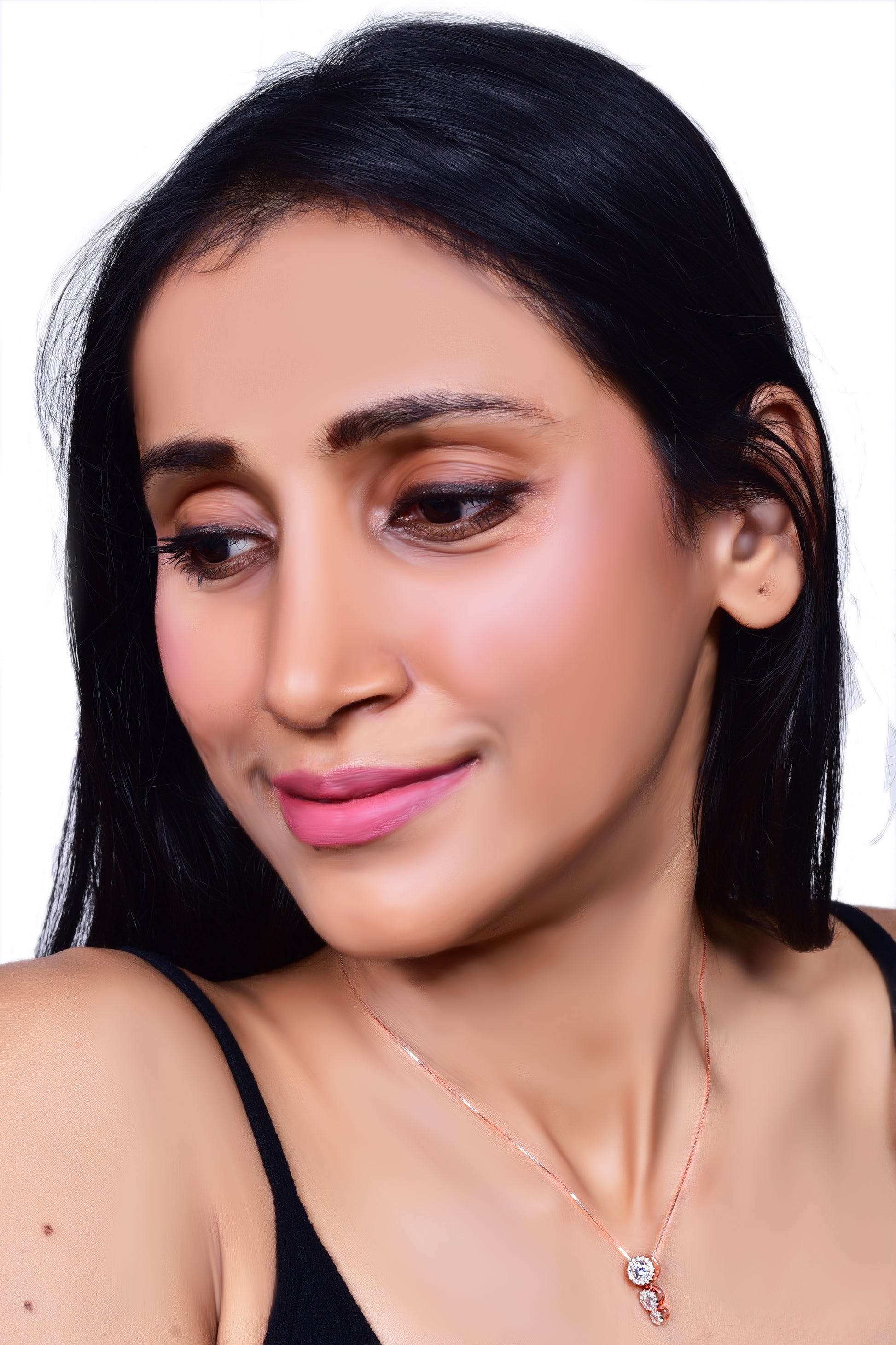 Elegant rose gold necklace featuring a three-stone drop pendant adorned with sparkling crystals, gracefully worn with a black outfit for a sophisticated look