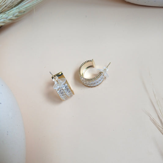 A pair of elegant gold-tone half-hoop earrings featuring baguette-cut cubic zirconia stones in a channel setting. The design combines classic sophistication with a modern touch, making them perfect for both everyday wear and special occasions.
