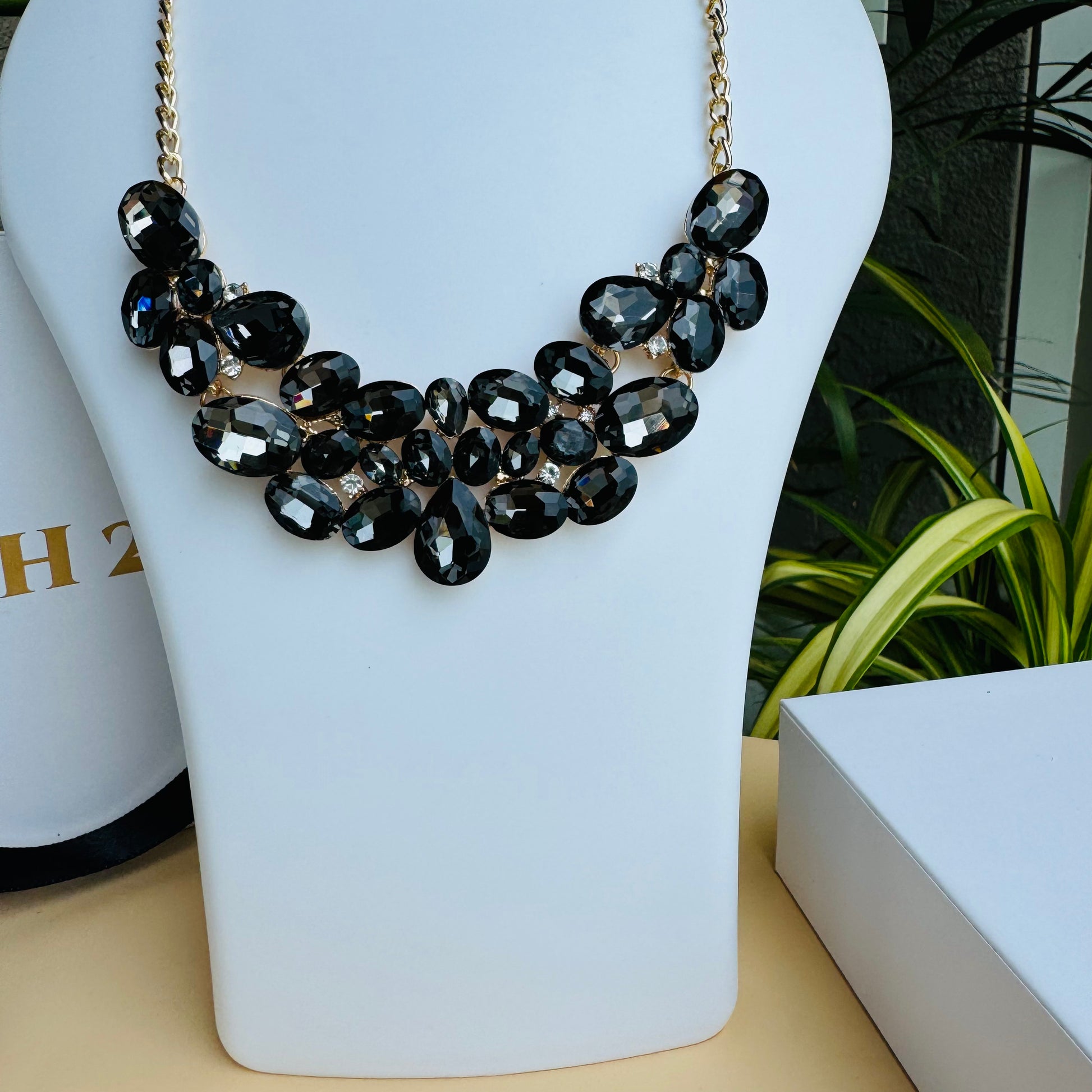 Ornate necklace with a floral or organic arrangement of black crystals on a delicate gold chain.