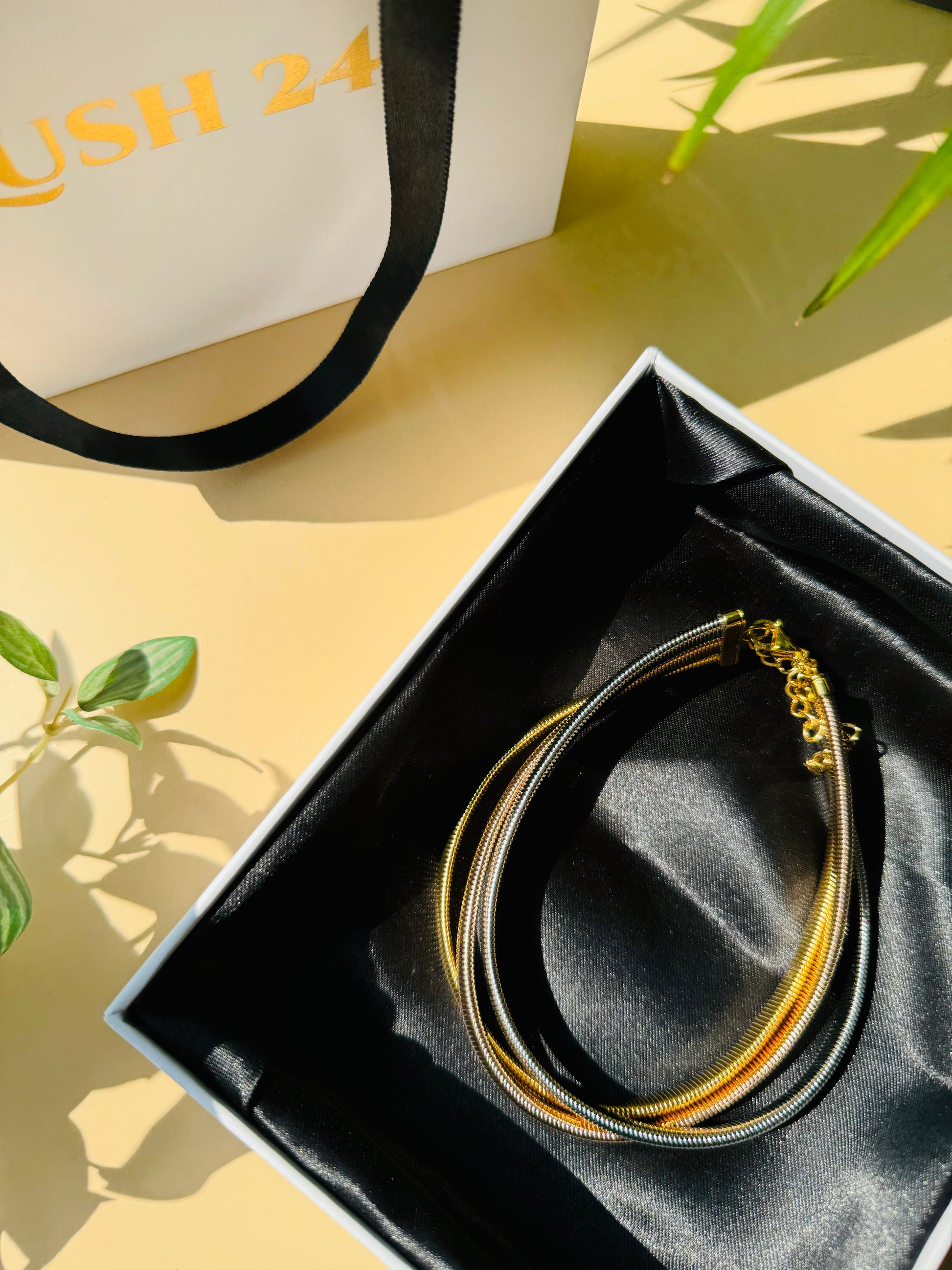 A chic triple-layer necklace from the Mumbai-based brand Lush 24, featuring delicate chains in bronze, silver, and gold. This versatile necklace is presented in a luxurious gift box with a black satin lining.