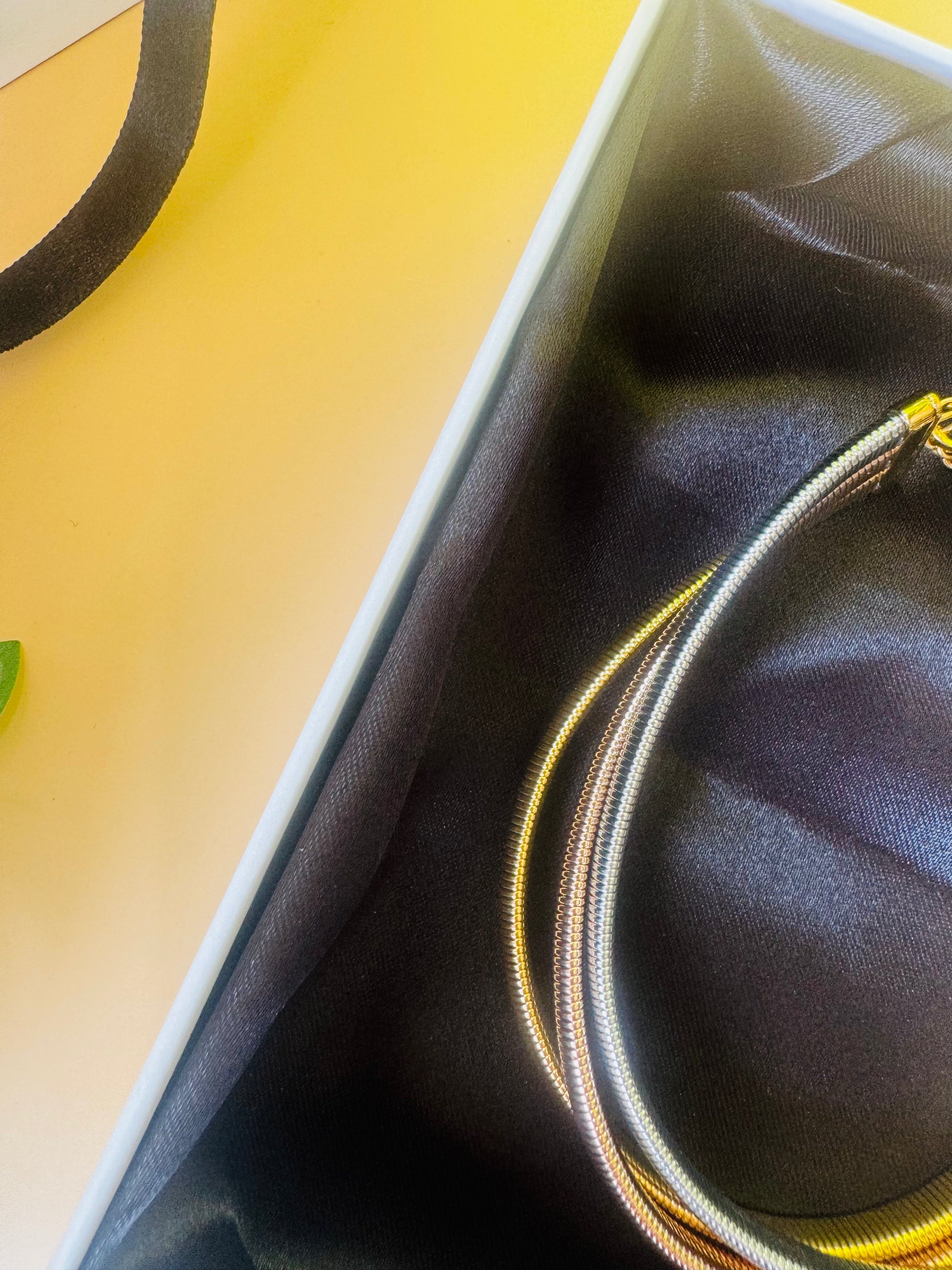 A chic triple-layer necklace from the Mumbai-based brand Lush 24, featuring delicate chains in bronze, silver, and gold. This versatile necklace is presented in a luxurious gift box with a black satin lining.