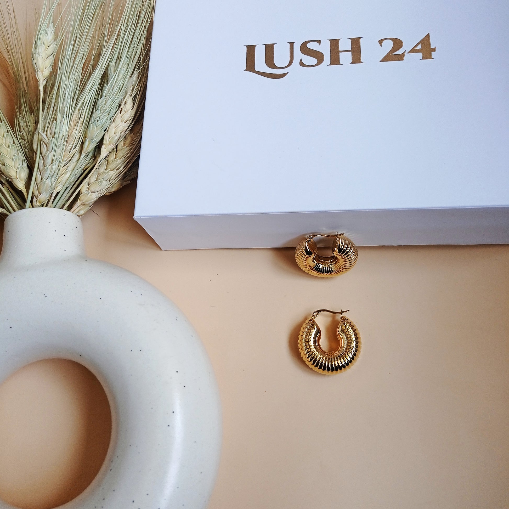 Elegant gold ridged hoop earrings with a vintage charm, styled with a luxe LUSH 24 box and neutral ceramic decor