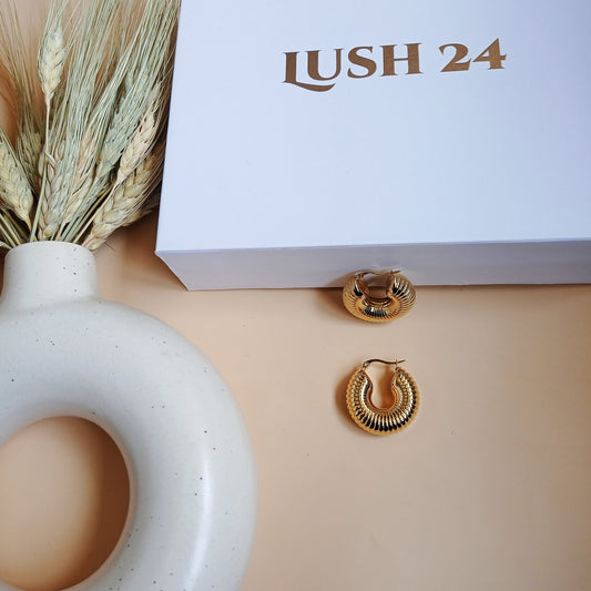 Elegant gold ridged hoop earrings with a vintage charm, styled with a luxe LUSH 24 box and neutral ceramic decor