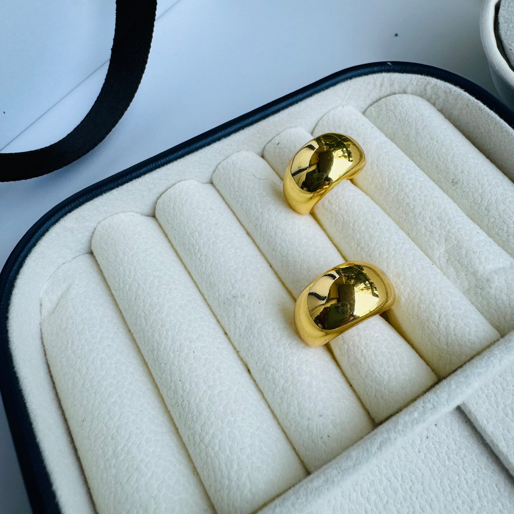 Classic gold stud earrings with a sleek, minimalist design, displayed in an elegant jewelry case for a timeless and sophisticated look