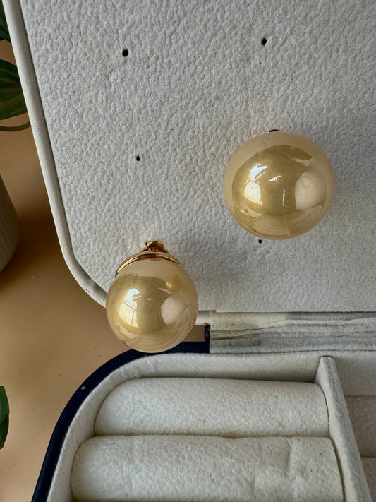Statement classic pearl studs in a warm gold tone. They are presented in a protective jewelry case, ready for wear.