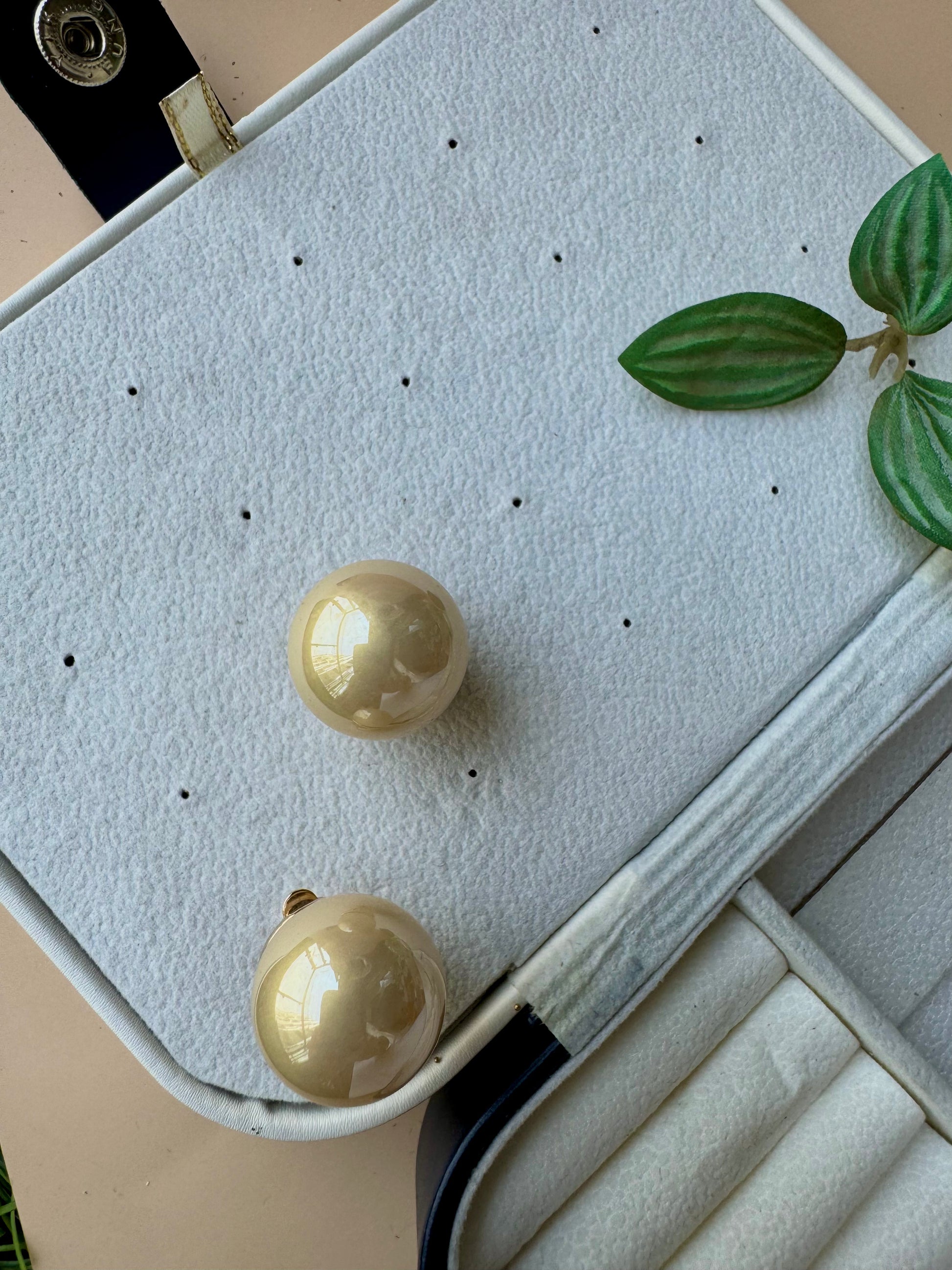 Statement classic pearl studs in a warm gold tone. They are presented in a protective jewelry case, ready for wear.