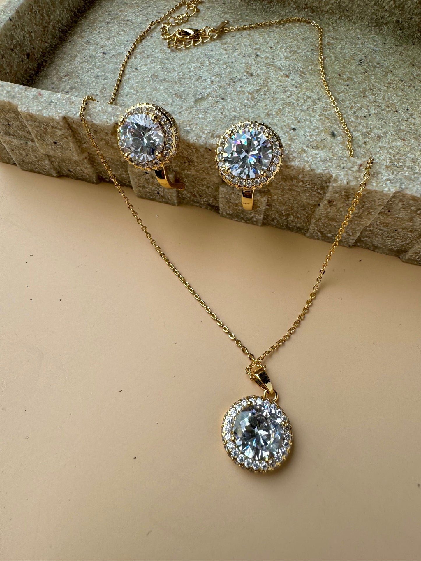 A beautiful jewelry set featuring a floral pendant necklace and matching stud earrings, adorned with clear crystals set in a silver-toned metal. The set is packaged in a light blue gift box with the gold "LUSH 24" logo