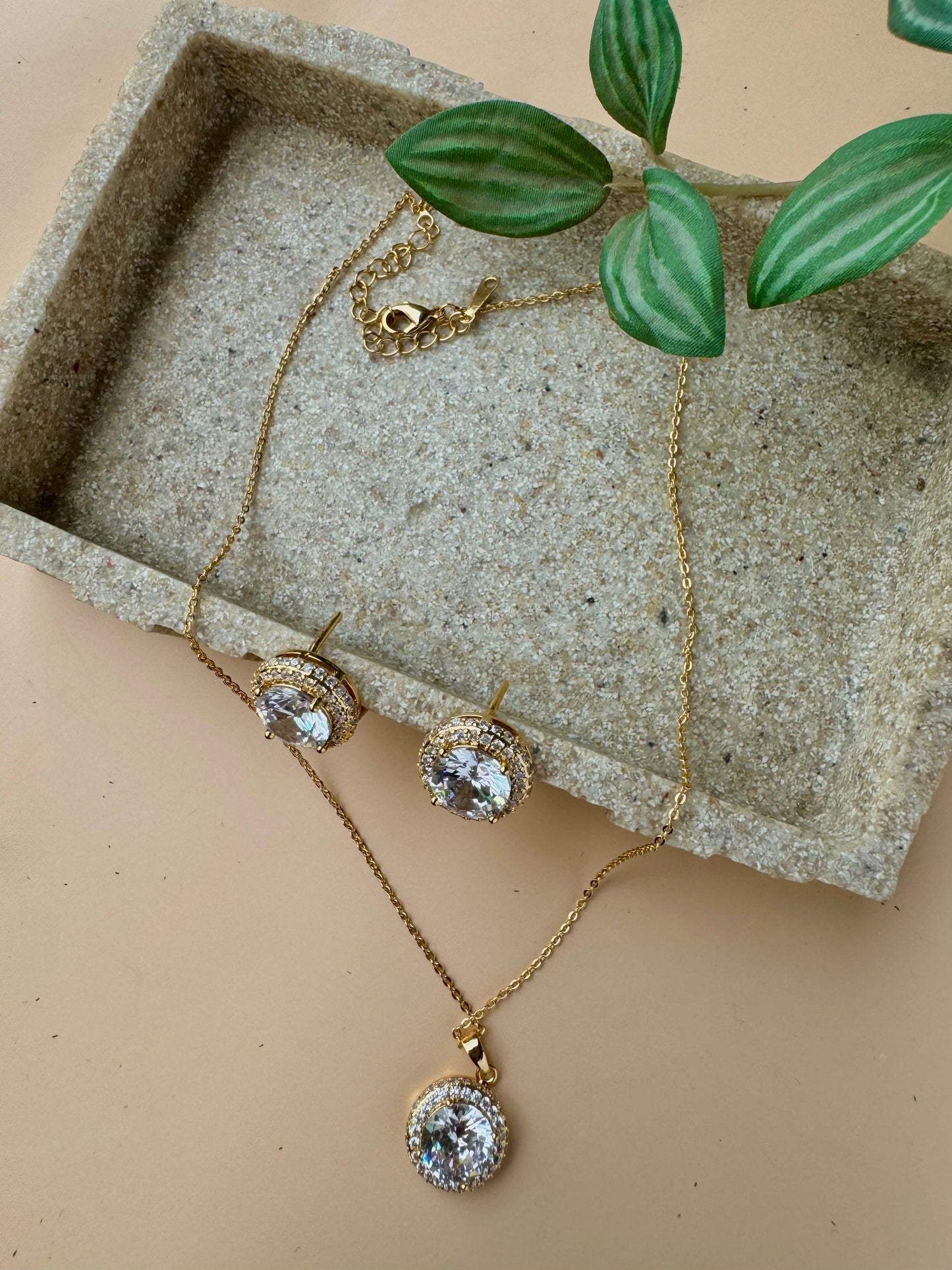 A beautiful jewelry set featuring a floral pendant necklace and matching stud earrings, adorned with clear crystals set in a silver-toned metal. The set is packaged in a light blue gift box with the gold "LUSH 24" logo
