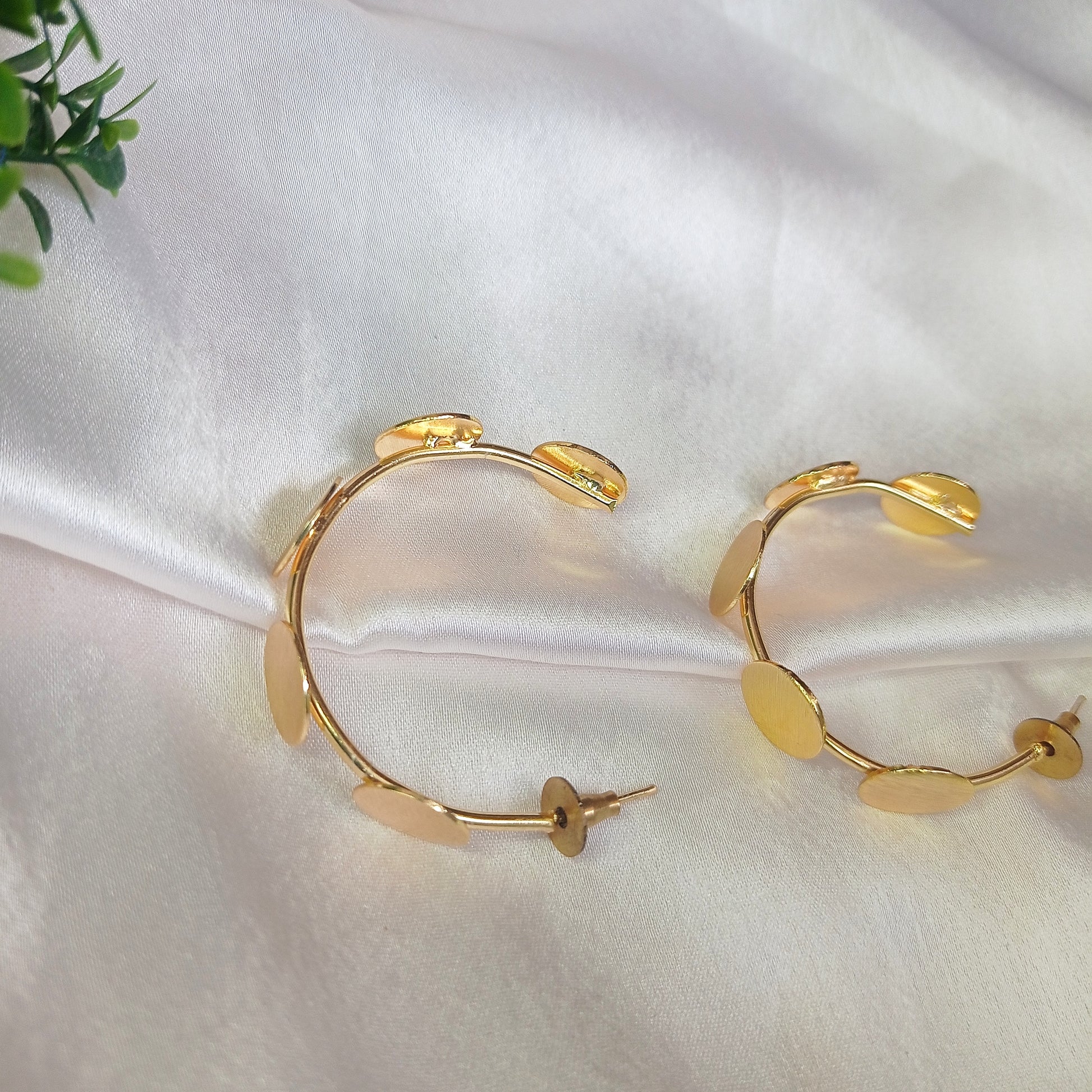 a woman wearing contemporary gold-tone statement earrings featuring multiple brushed metal discs in an artistic, asymmetric arrangement. The earrings have a modern, elegant look, perfect for adding a touch of sophistication to any outfit.