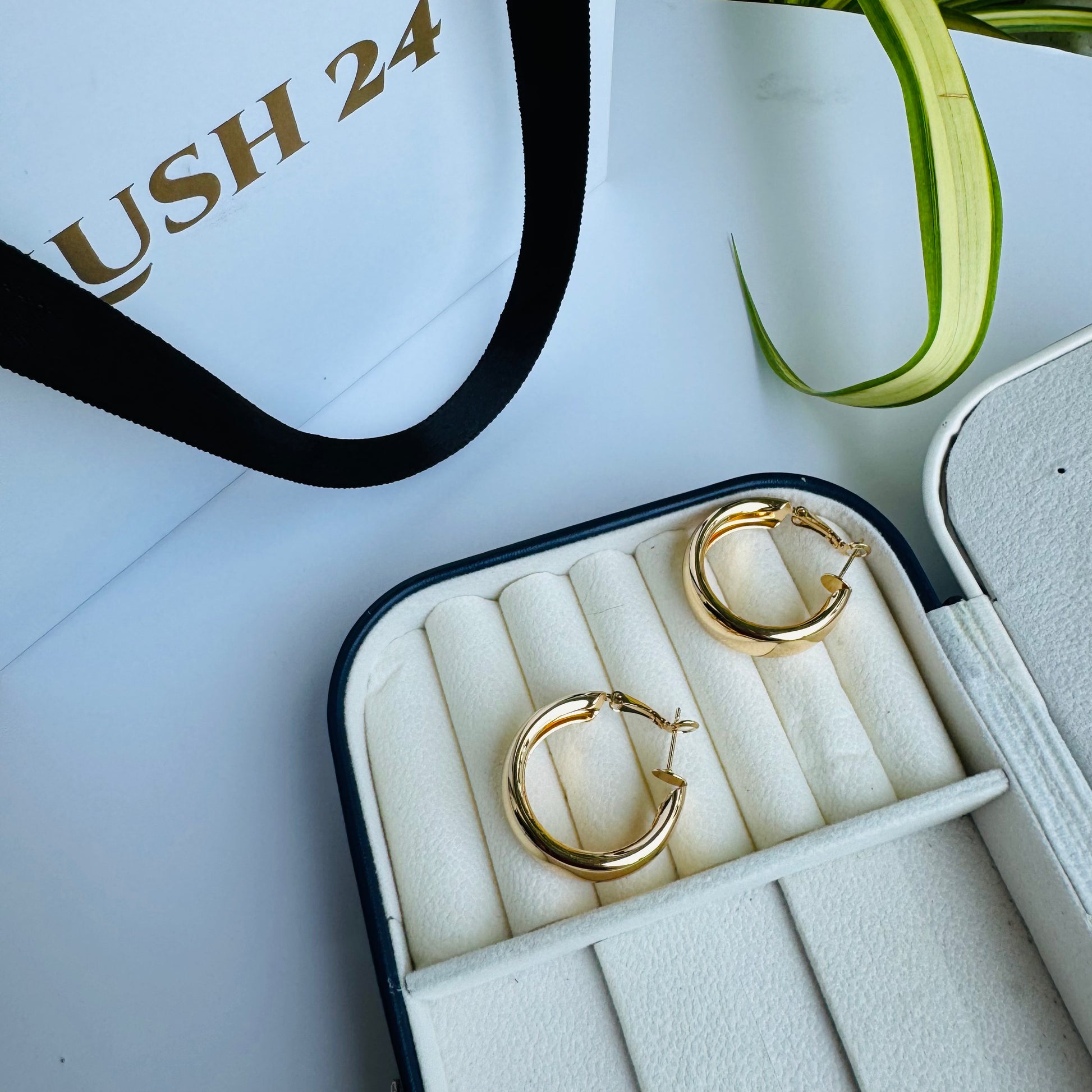 Pair of shiny gold hoop earrings in a white and black jewelry case