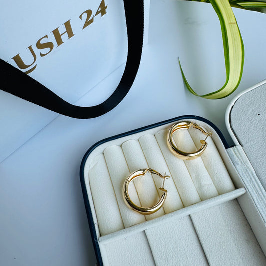 Pair of shiny gold hoop earrings in a white and black jewelry case