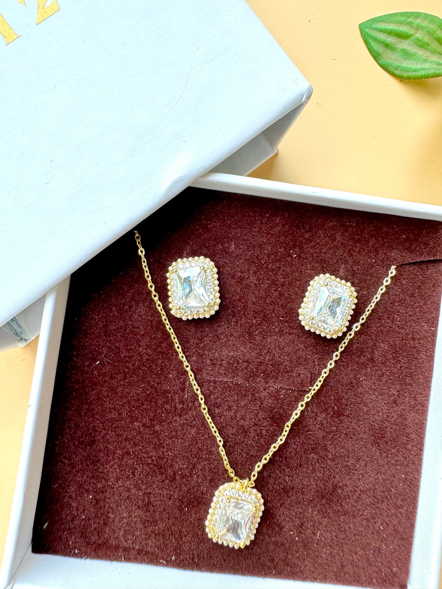 Elegant flower-shaped crystal pendant necklace and earring set displayed in a light blue and white LUSH 24 gift box.