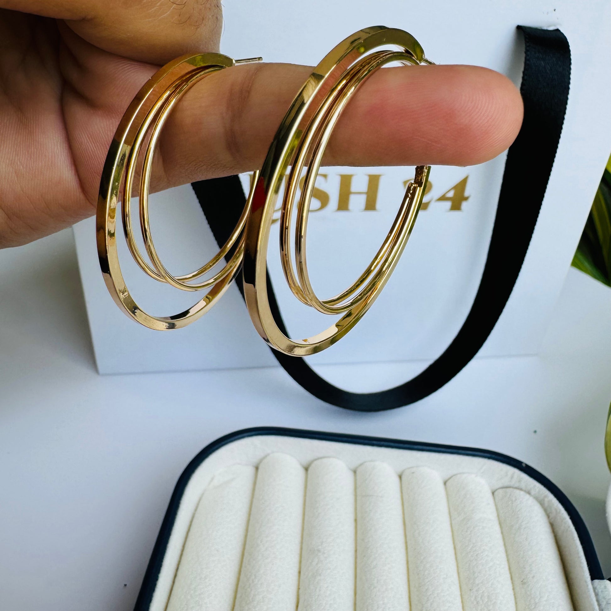 Pair of slender gold hoop earrings in a jewelry case.