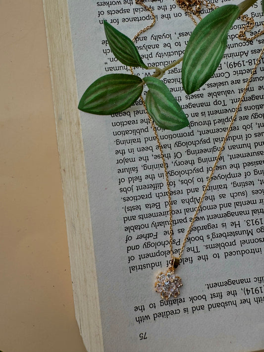 Elegant flower pendant necklace with a modern pendant that resembles a stack of miniature flower, one of which is pavé-set with clear stones. This design is inspired by iconic jewelry styles and could be found in Mumbai.