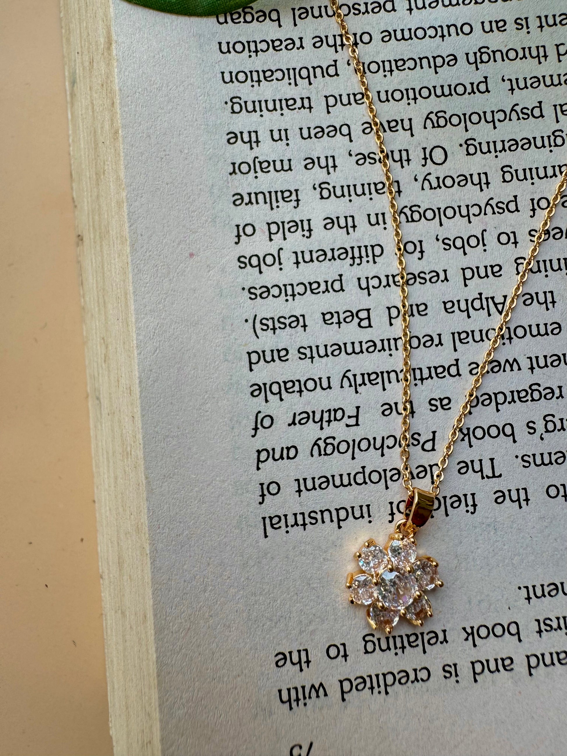 Elegant flower pendant necklace with a modern pendant that resembles a stack of miniature flower, one of which is pavé-set with clear stones. This design is inspired by iconic jewelry styles and could be found in Mumbai.
