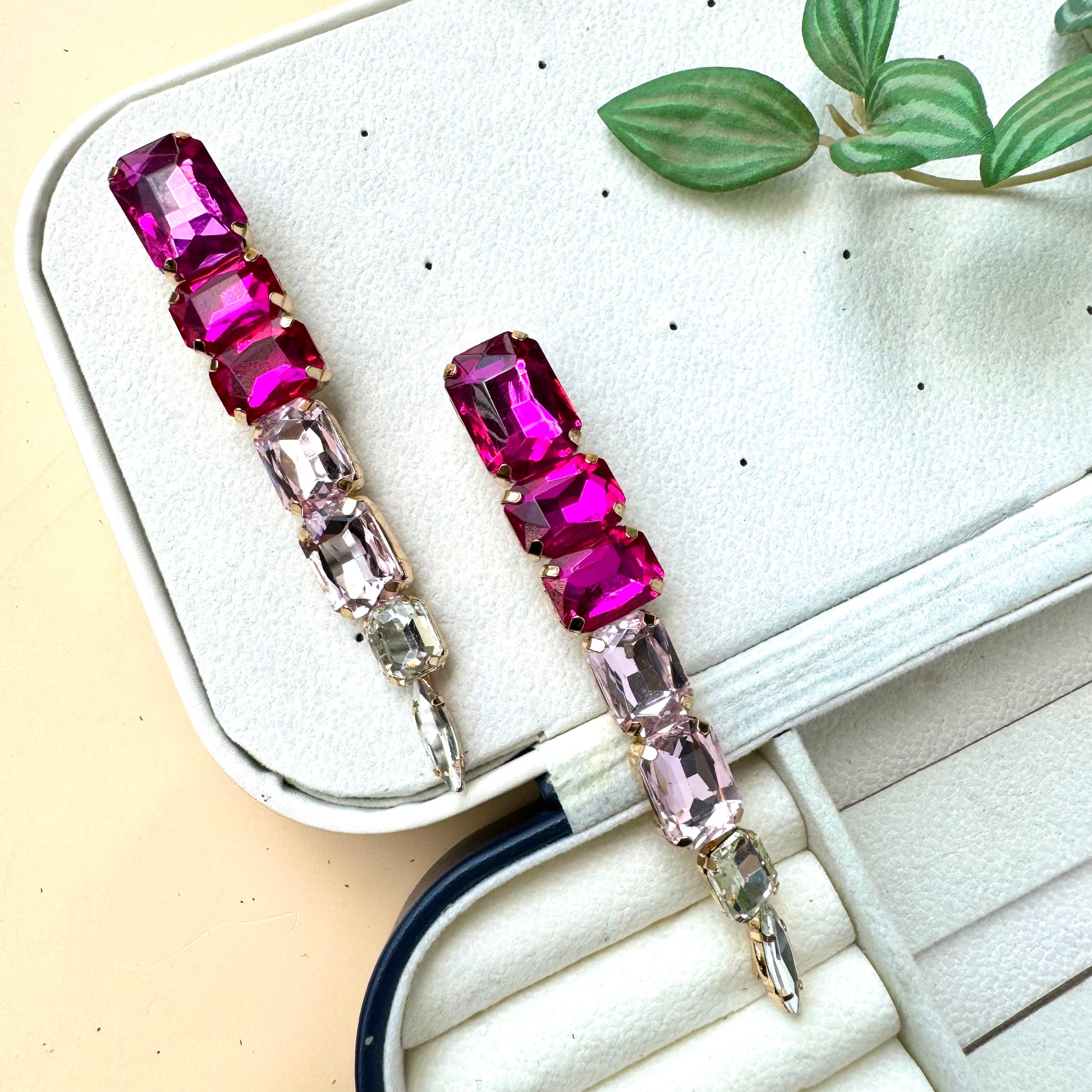 Elegant gradient gemstone drop earrings featuring vibrant pink and blush-toned rectangular crystals, set in gold-tone metal, displayed on a soft jewelry case
