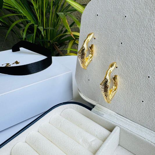 Abstractly shaped gold earrings displayed on a jewelry stand