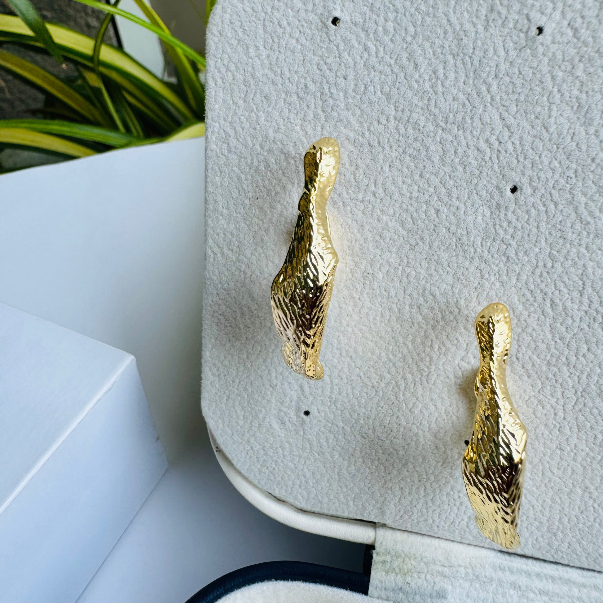 Abstractly shaped gold earrings displayed on a jewelry stand