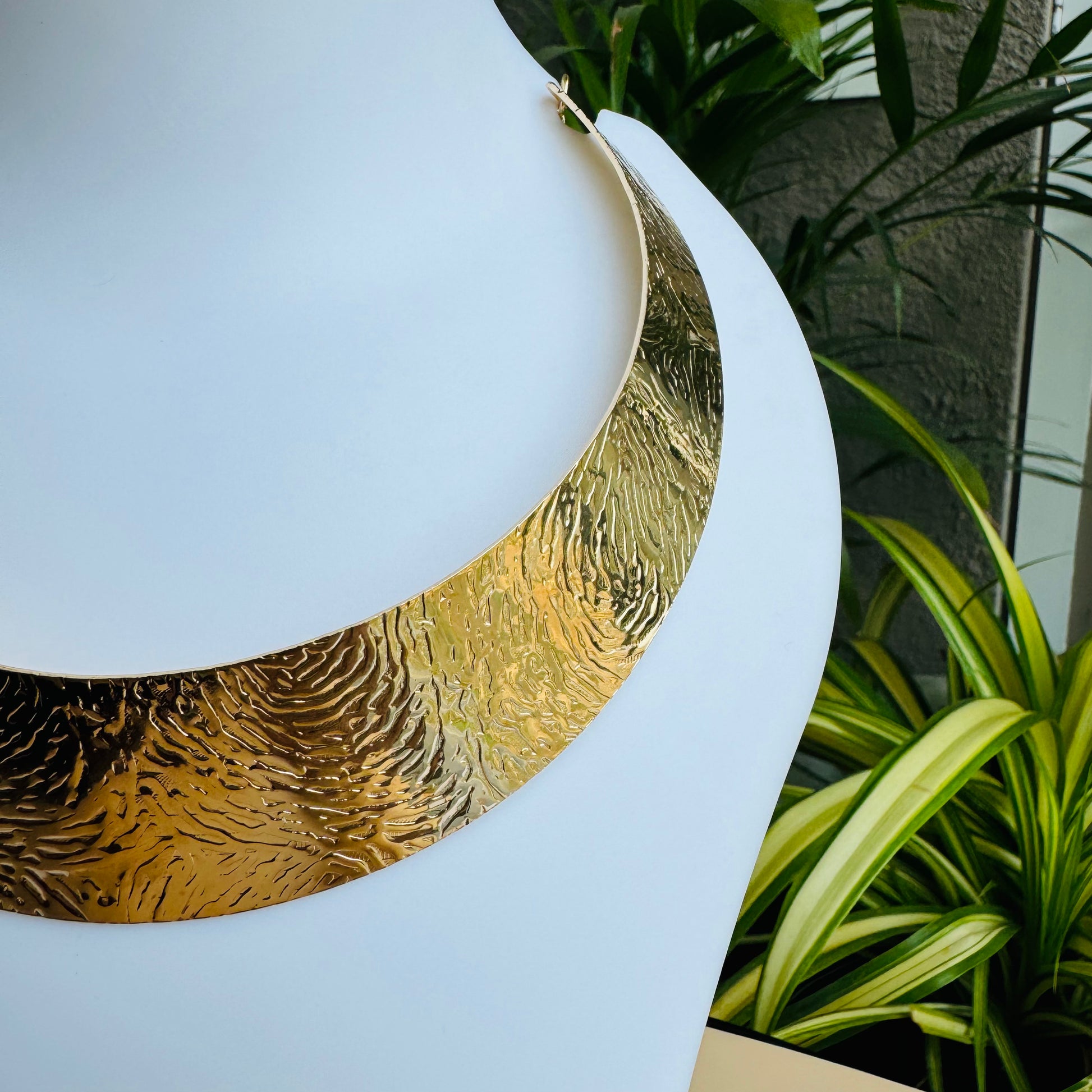 A dramatic gold metallic collar necklace with radiating spikes is displayed on a white mannequin bust. Lush 24 branded shopping bags and a jewelry box are visible in the background.